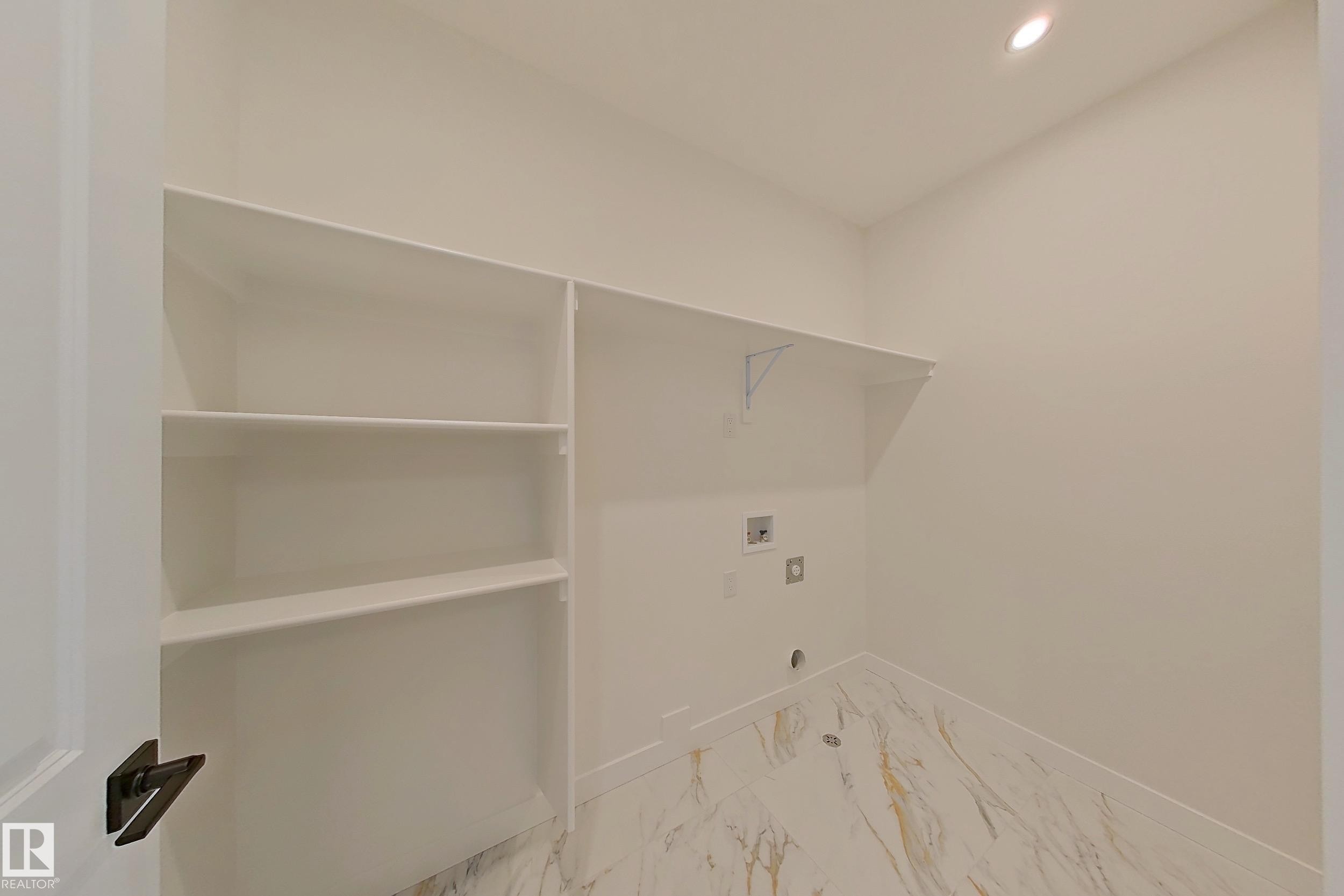 Laundry area with built-in shelving, a wall-mounted shelf, and marble-style flooring - 17 Trill Point(E), Spruce Grove, AB - Indoor With Storage