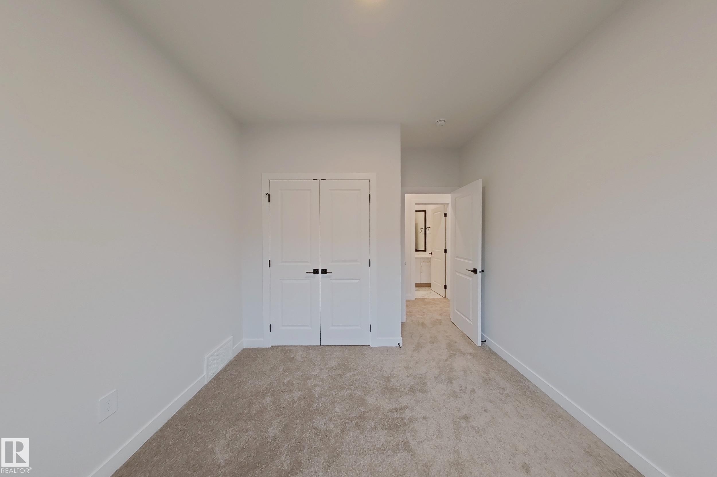This room features light-colored carpet, white walls, and a closet with double doors - 17 Trill Point(E), Spruce Grove, AB - Indoor Photo Showing Other Room