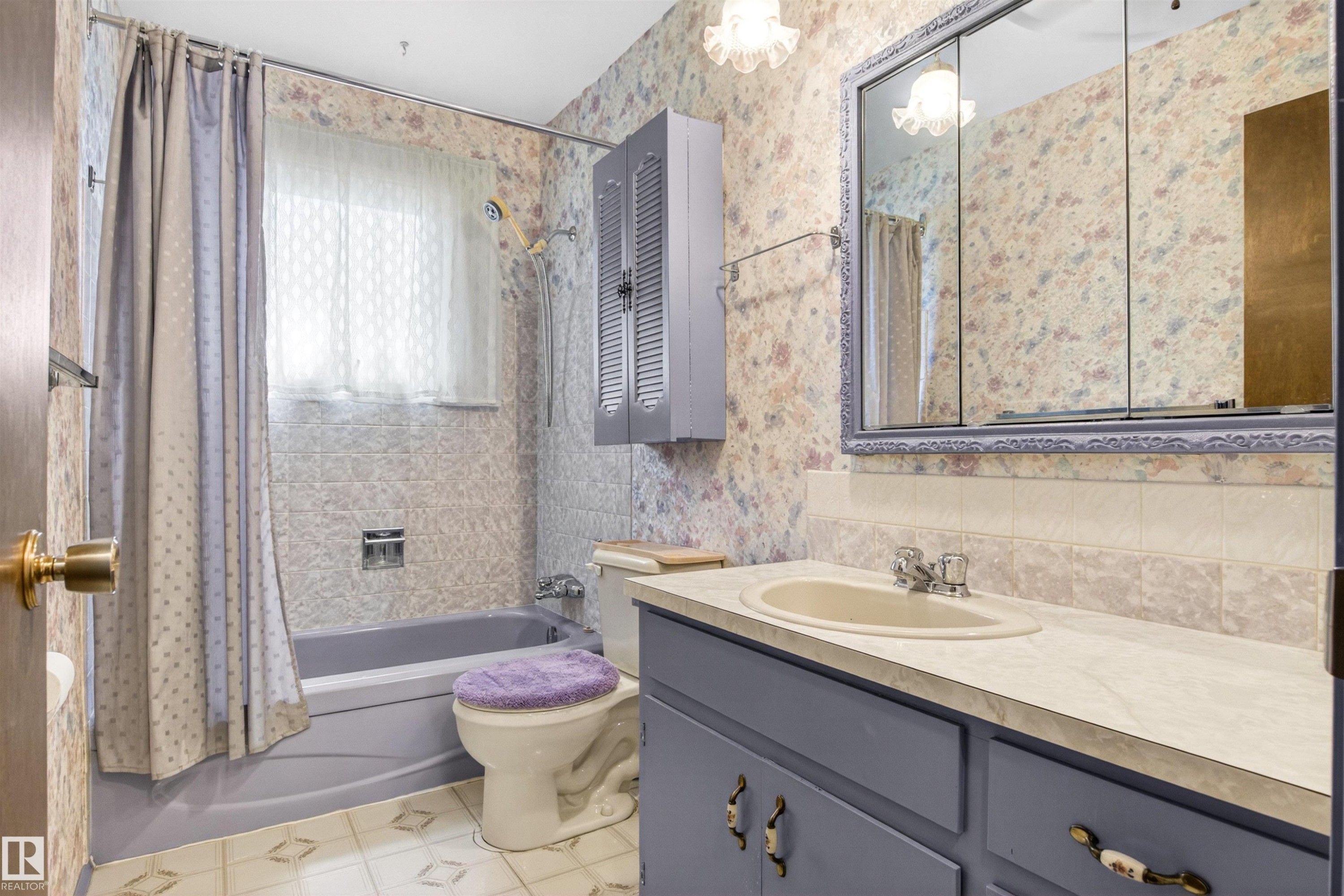 Full bathroom featuring a vanity with an integrated sink, a medicine cabinet with a decorative frame, and a bathtub with a tiled surround - 29 Bristow Crescent, Spruce Grove, AB - Indoor Photo Showing Bathroom