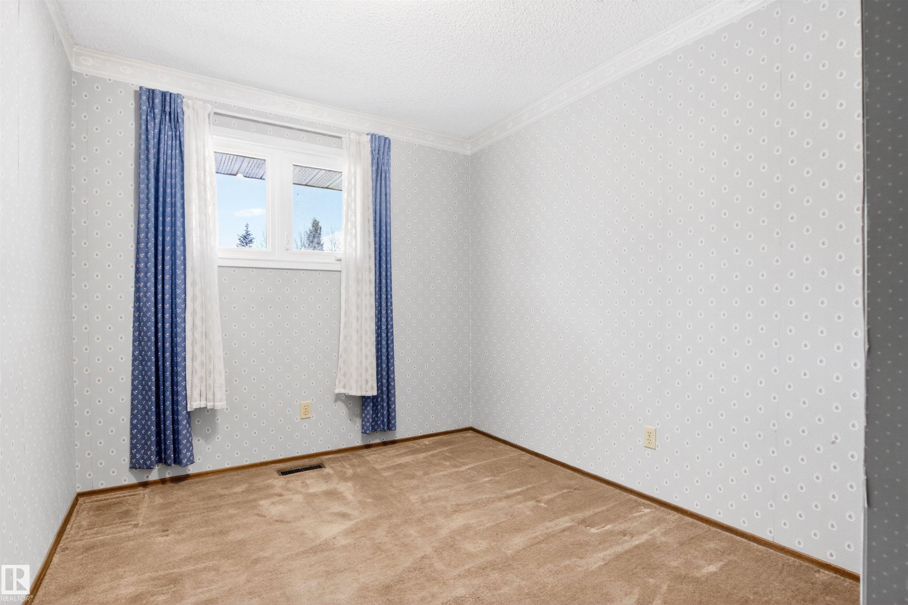 Carpeted room featuring light-toned patterned wallpaper, white crown molding, and a white-framed window - 29 Bristow Crescent, Spruce Grove, AB - Indoor Photo Showing Other Room