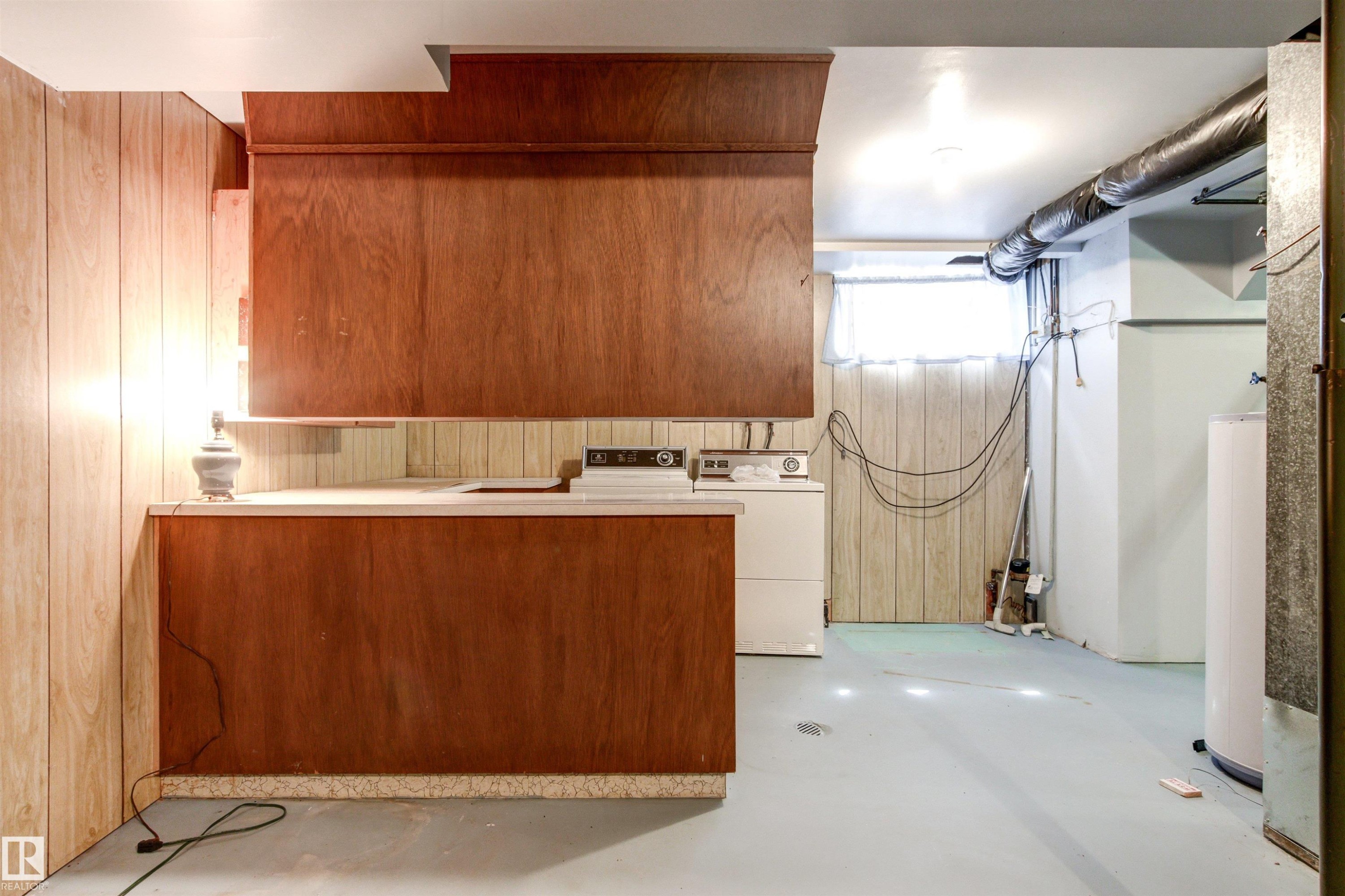 Utility space featuring wood paneling, built-in cabinetry, a counter, and a window - 29 Bristow Crescent, Spruce Grove, AB - Indoor Photo Showing Laundry Room