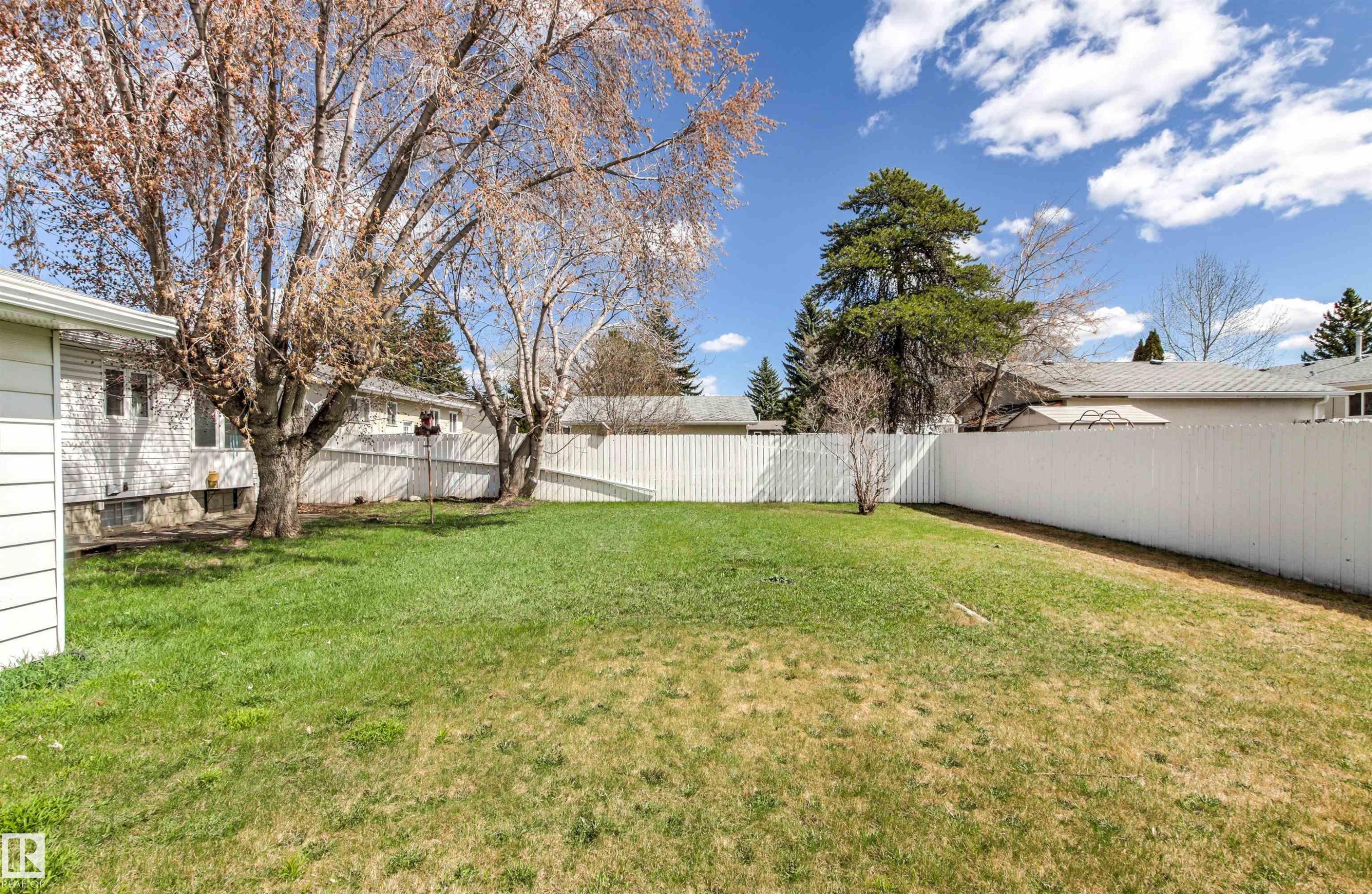 Expansive backyard featuring a manicured lawn, mature deciduous trees, and privacy fencing - 29 Bristow Crescent, Spruce Grove, AB - Outdoor