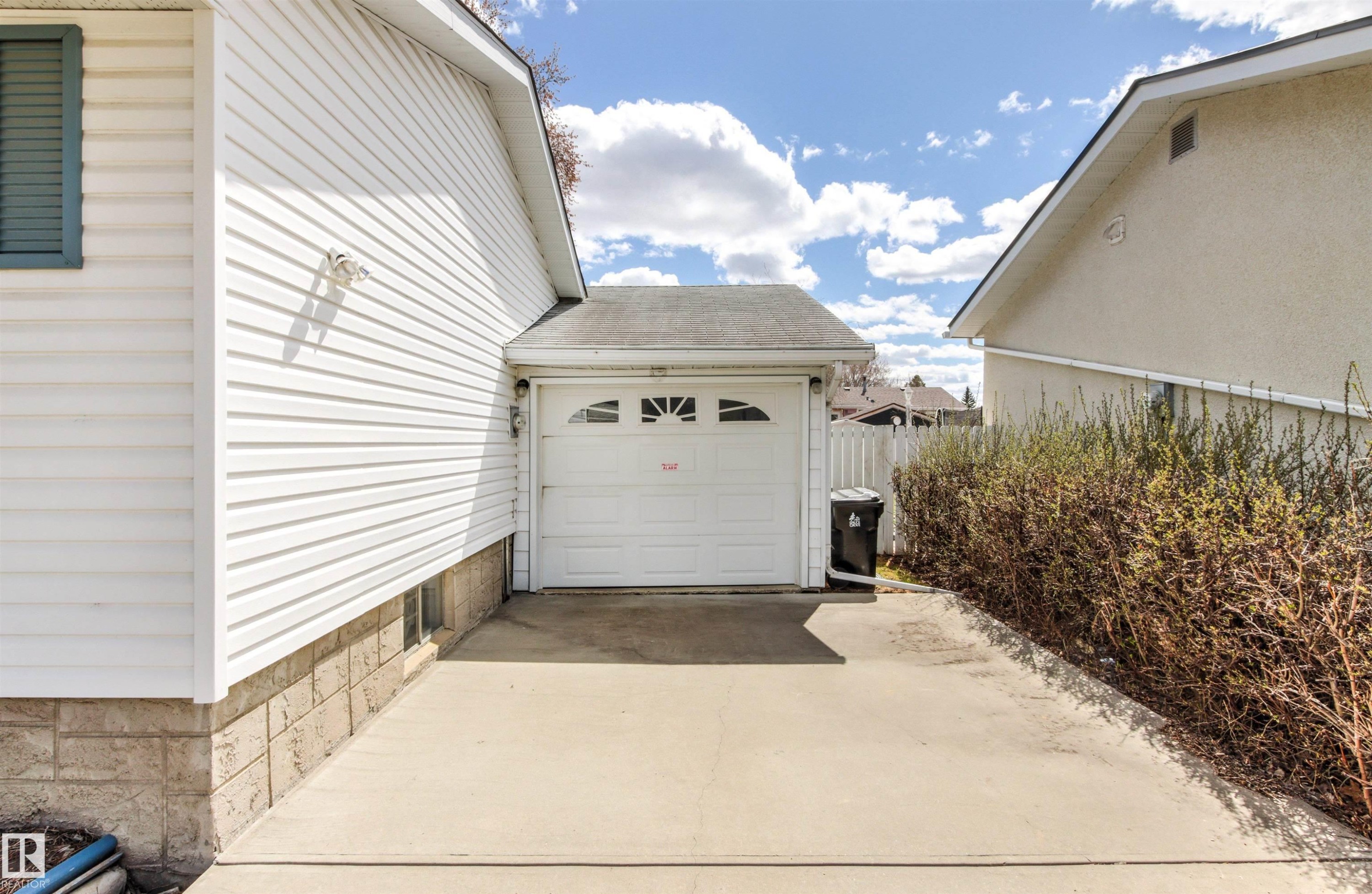Single-car garage with arched window detailing, concrete driveway, and white vinyl siding - 29 Bristow Crescent, Spruce Grove, AB - Outdoor With Exterior