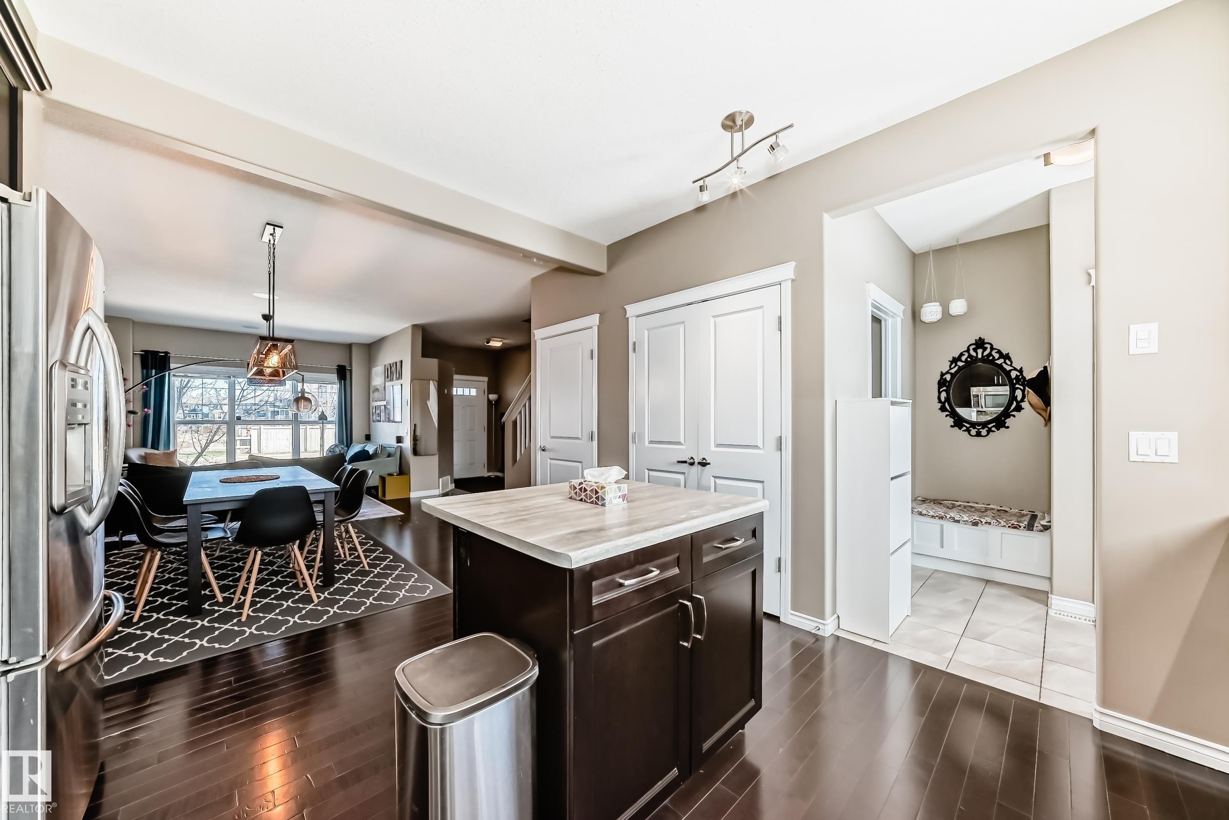 Kitchen island with a light-toned countertop, dark wood-finish cabinetry, and stainless steel hardware - 5020 Orchards Gate, Edmonton, AB - Indoor Photo Showing Other Room