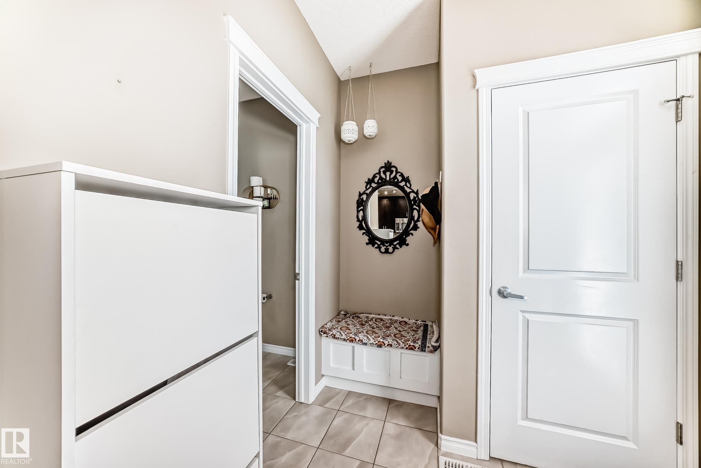 Entryway featuring tile flooring, a built-in storage bench, a decorative mirror, and a modern pendant light fixture - 5020 Orchards Gate, Edmonton, AB - Indoor Photo Showing Other Room