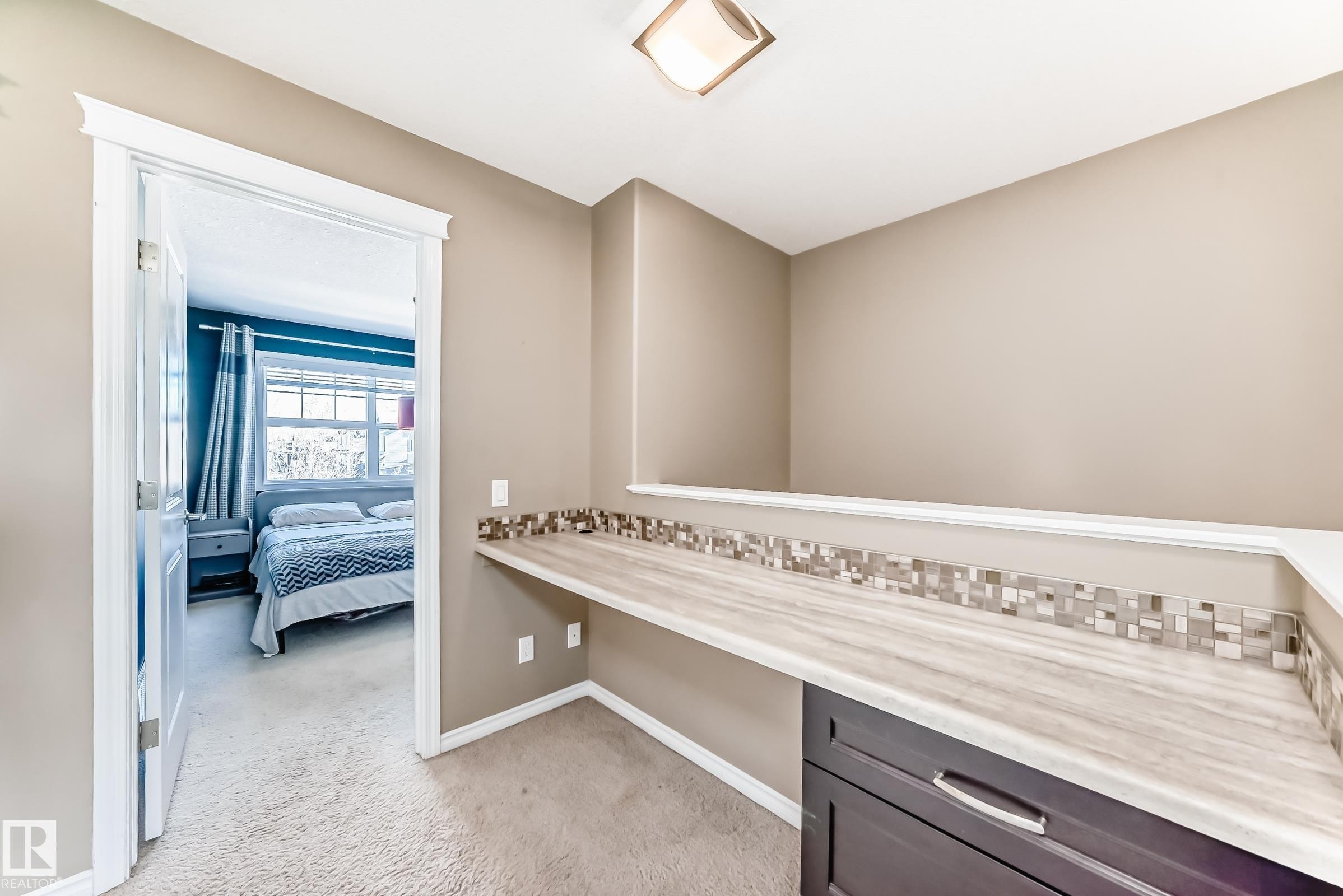 Built-in desk area featuring a wood-finish countertop, mosaic tile backsplash, and dark wood cabinetry - 5020 Orchards Gate, Edmonton, AB - Indoor