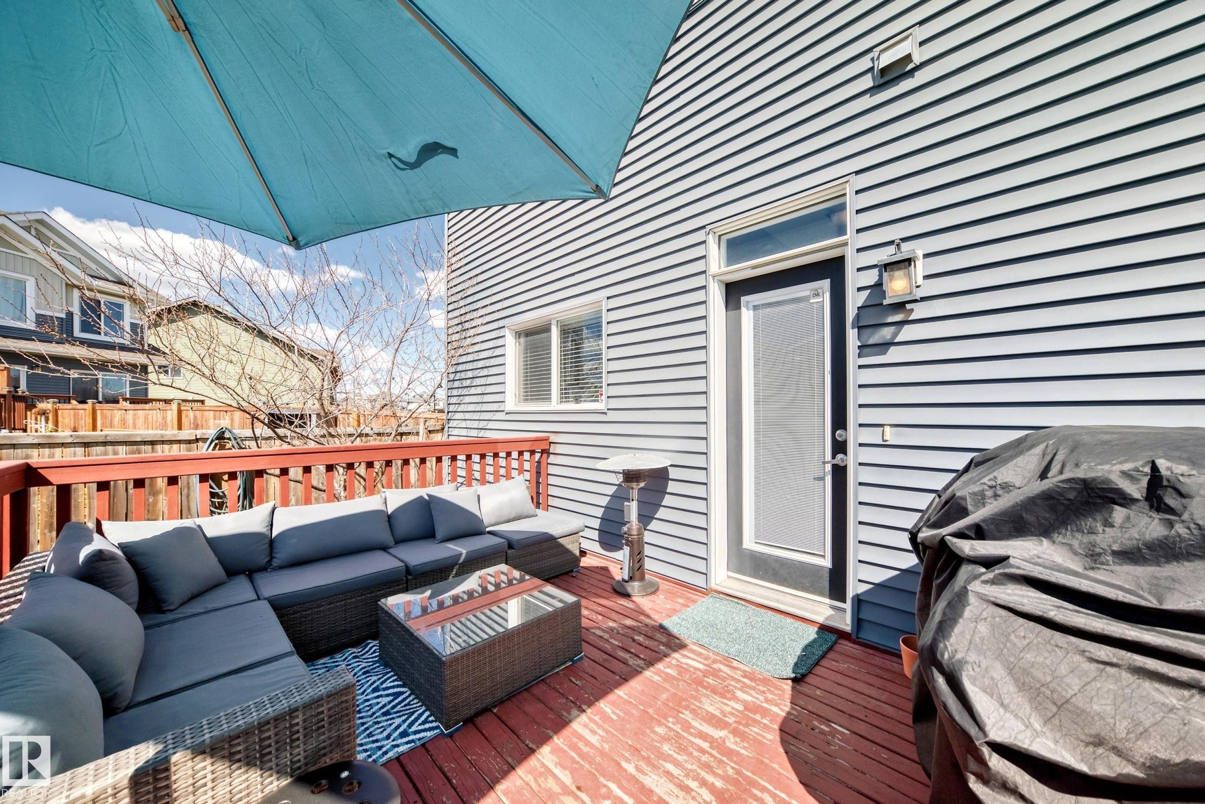 Spacious outdoor deck featuring red-stained wood planks, a coordinating red railing, and light blue siding - 5020 Orchards Gate, Edmonton, AB - Outdoor With Deck Patio Veranda With Exterior