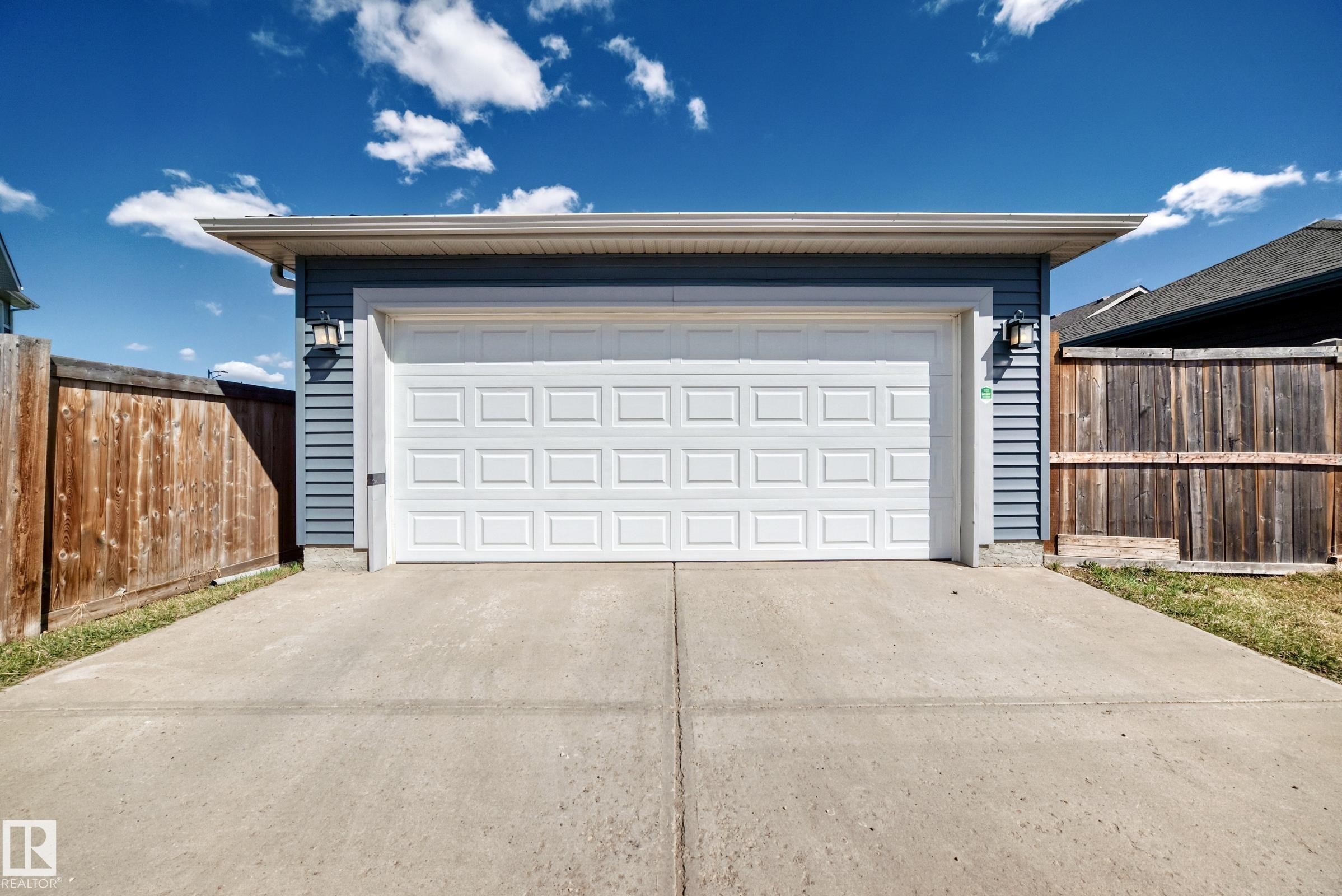 Attached garage featuring horizontal siding and a white paneled door - 5020 Orchards Gate, Edmonton, AB - Outdoor