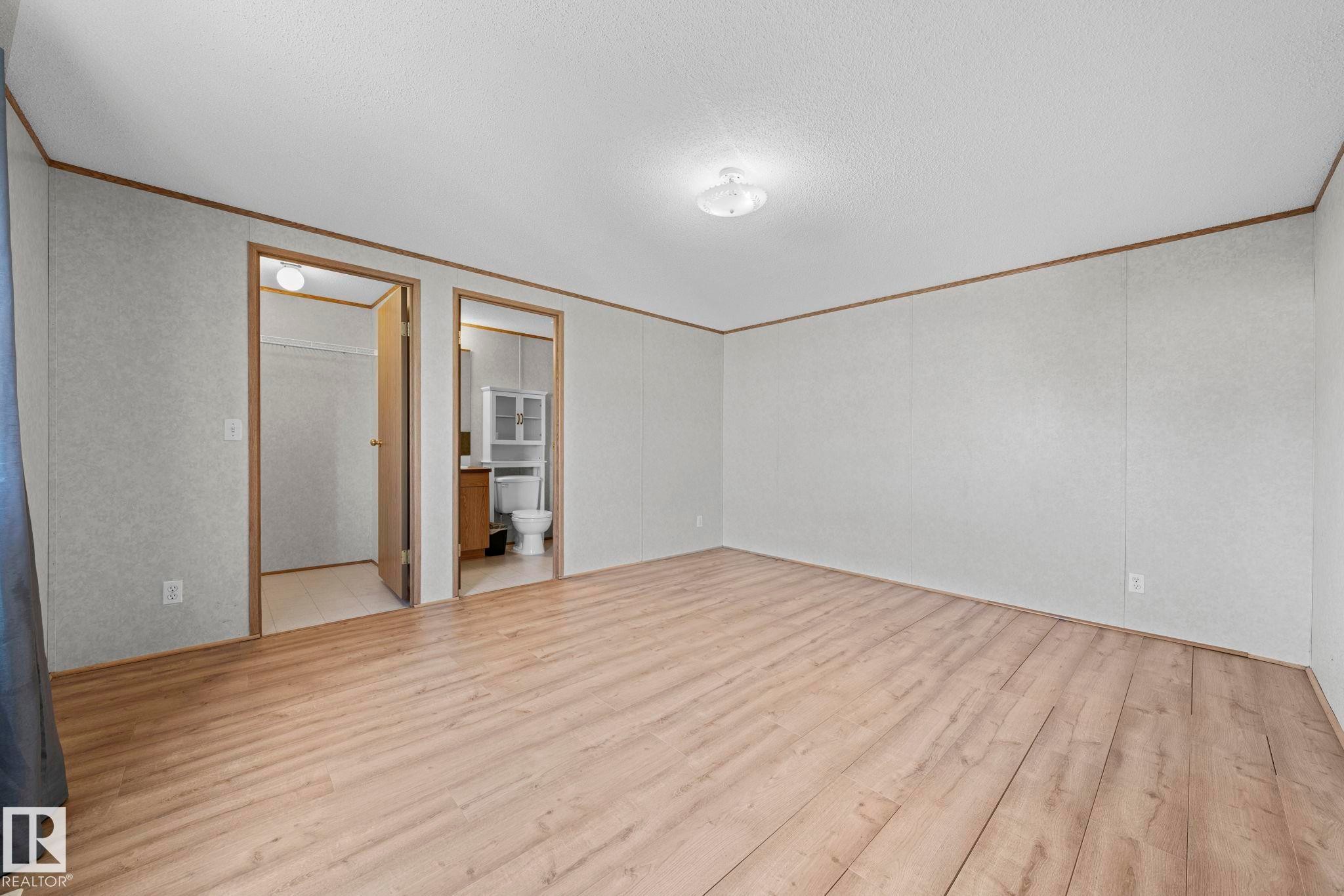 Spacious room featuring wood-finish flooring, white panel walls, and a ceiling-mounted light fixture - 623 Evergreen Park, Edmonton, AB - Indoor Photo Showing Other Room