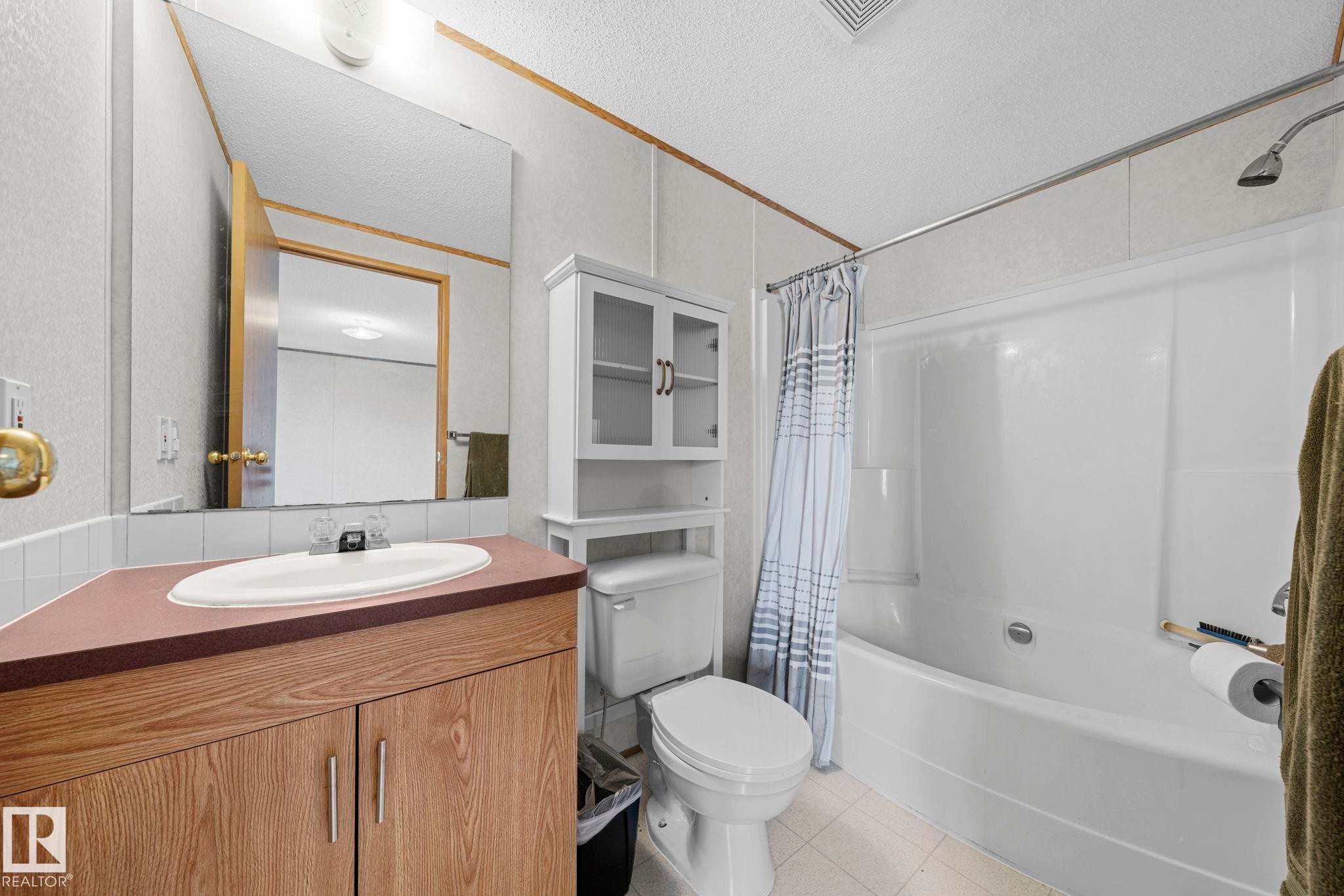 Bathroom featuring a wood-finish vanity with an integrated sink, a large wall mirror, and a white shower/tub combination - 623 Evergreen Park, Edmonton, AB - Indoor Photo Showing Bathroom