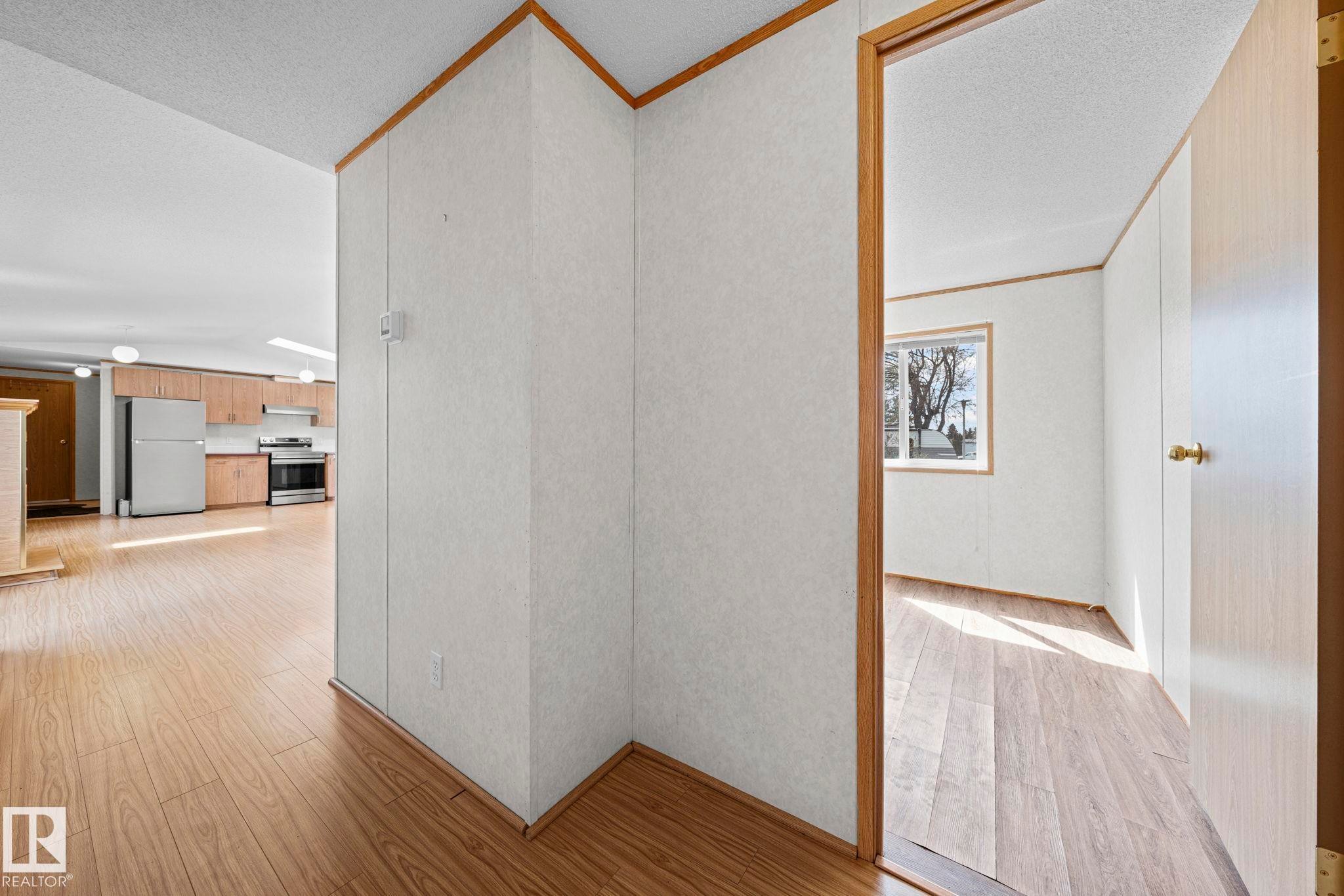 Open-concept interior featuring wood-finish flooring, light-toned wall panels, and contrasting wood trim - 623 Evergreen Park, Edmonton, AB - Indoor Photo Showing Other Room