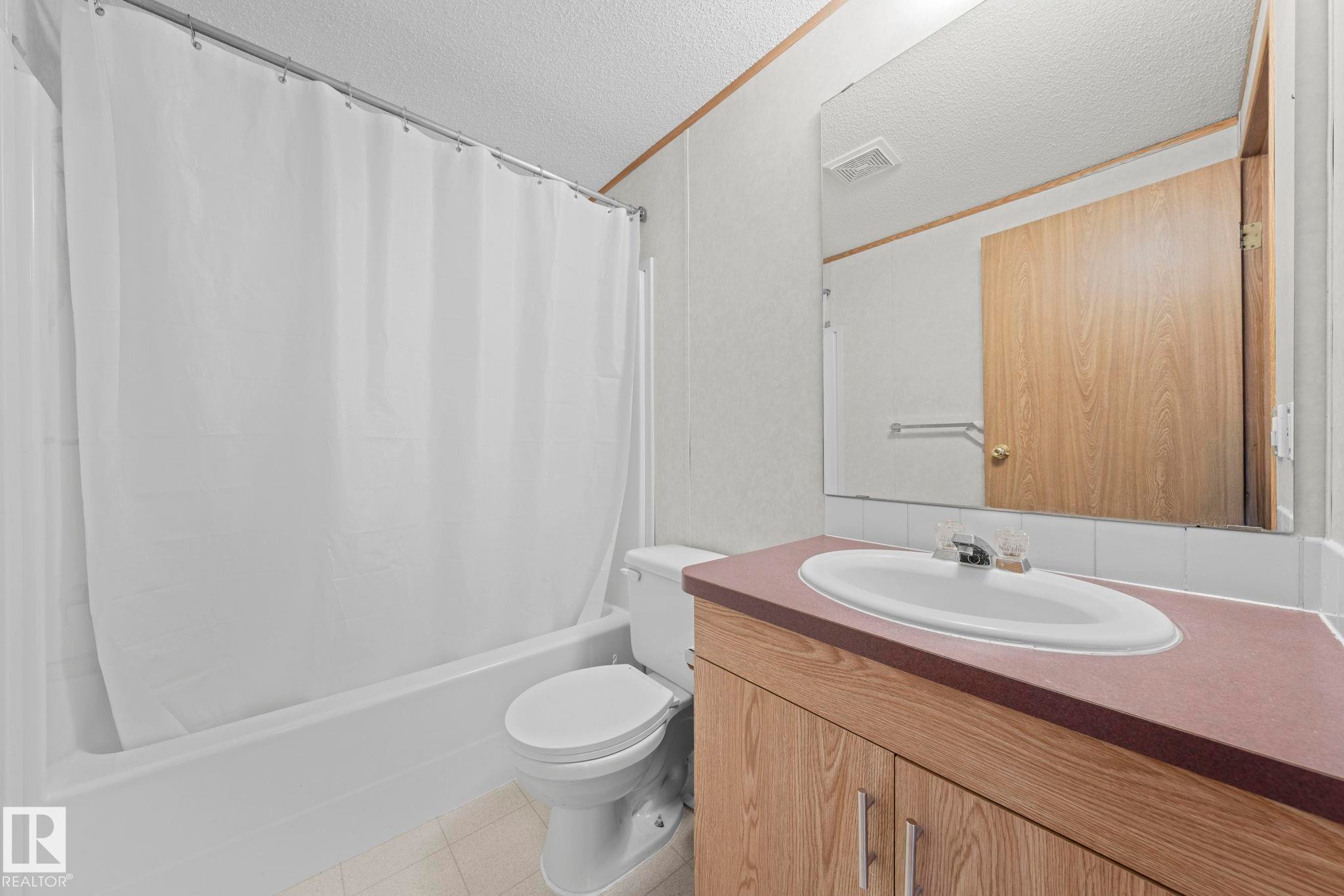 Bathroom featuring a bathtub with shower, white shower curtain, and a standard toilet - 623 Evergreen Park, Edmonton, AB - Indoor Photo Showing Bathroom
