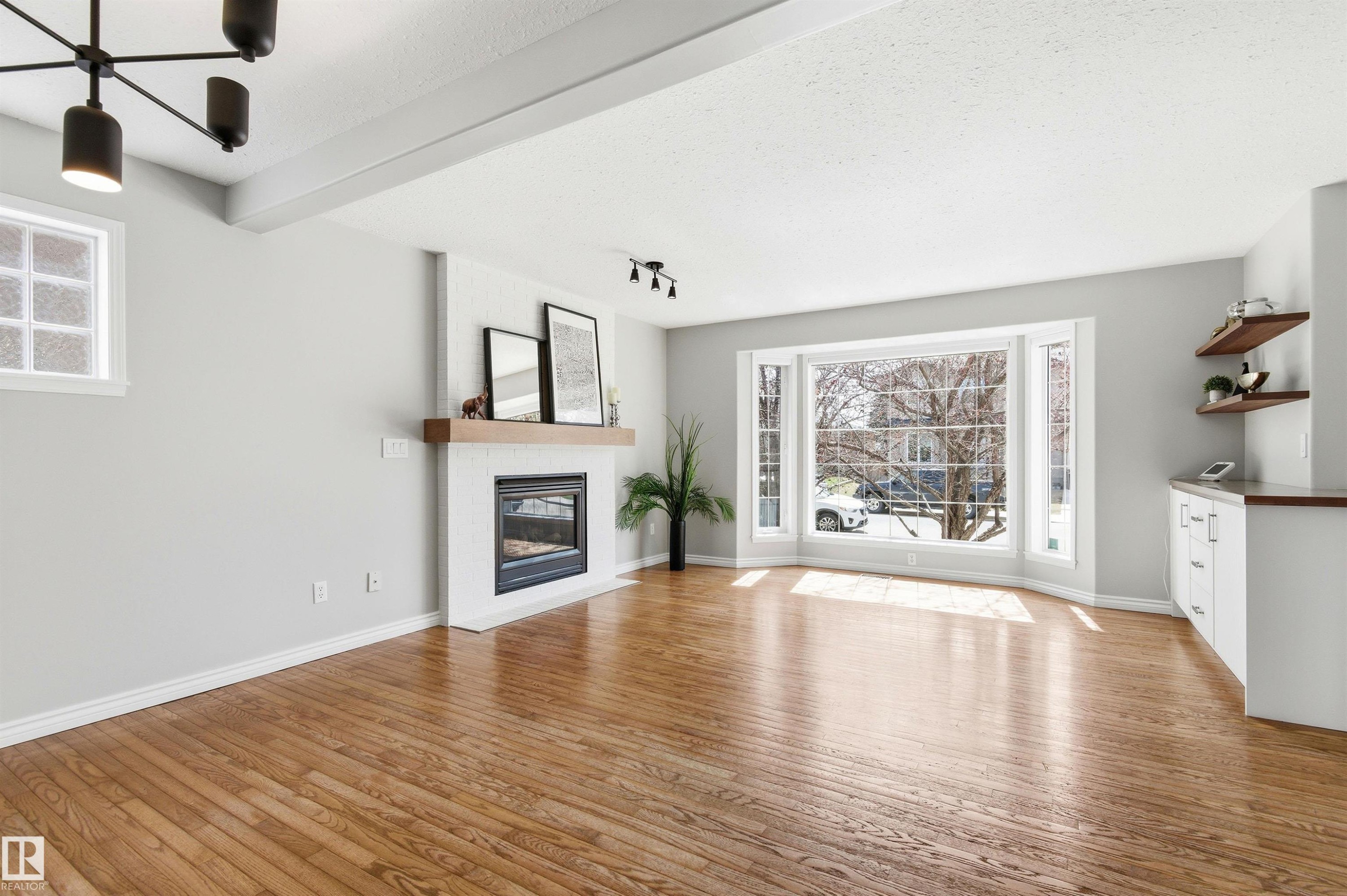 Hardwood flooring throughout featuring a modern fireplace with a wood mantel - 8730 92A Avenue, Edmonton, AB - Indoor Photo Showing Living Room With Fireplace