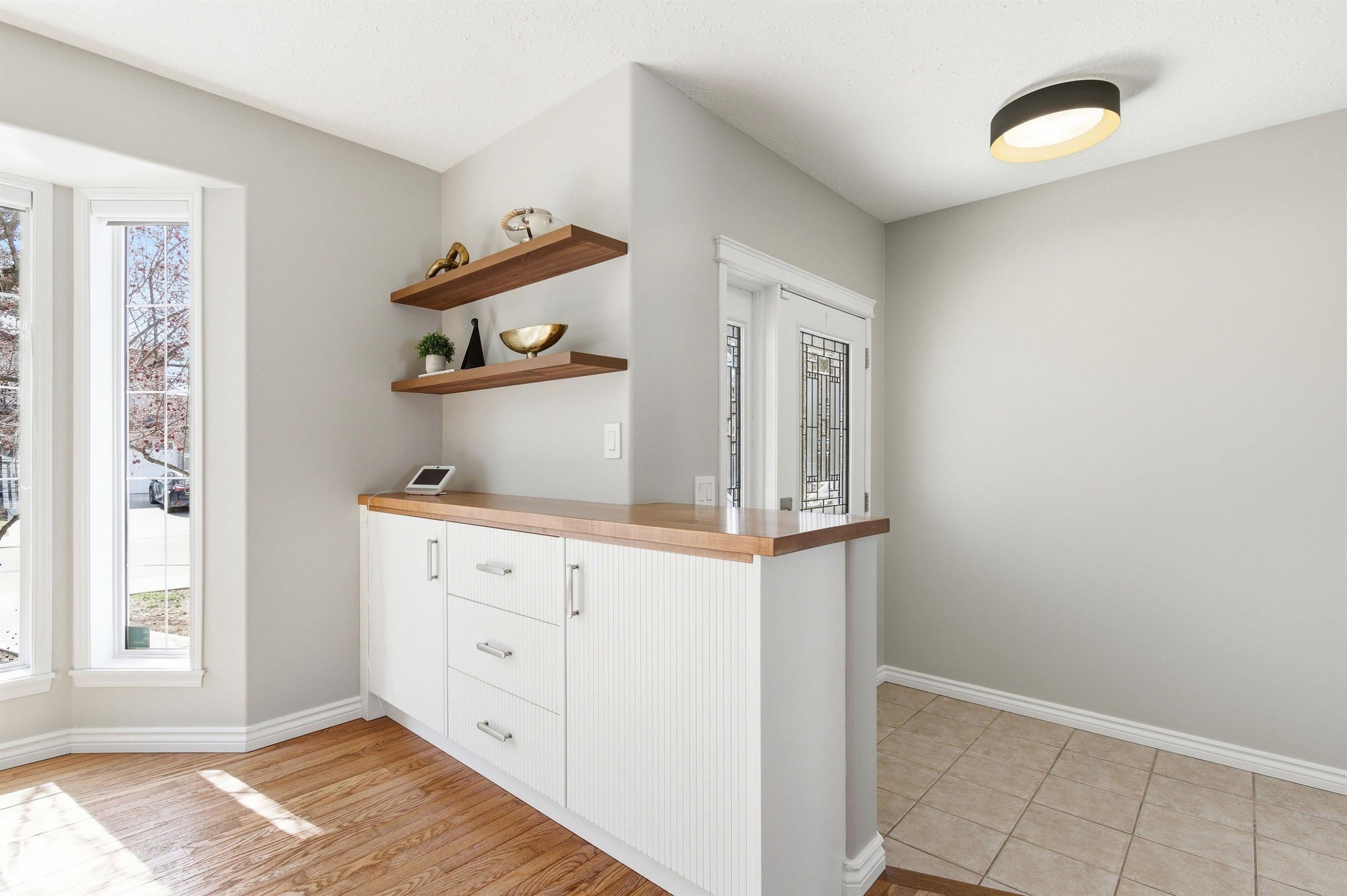 Integrated custom cabinetry with a wood-finish countertop, floating wood-finish shelving, and a decorative frosted glass entry door - 8730 92A Avenue, Edmonton, AB - Indoor Photo Showing Other Room