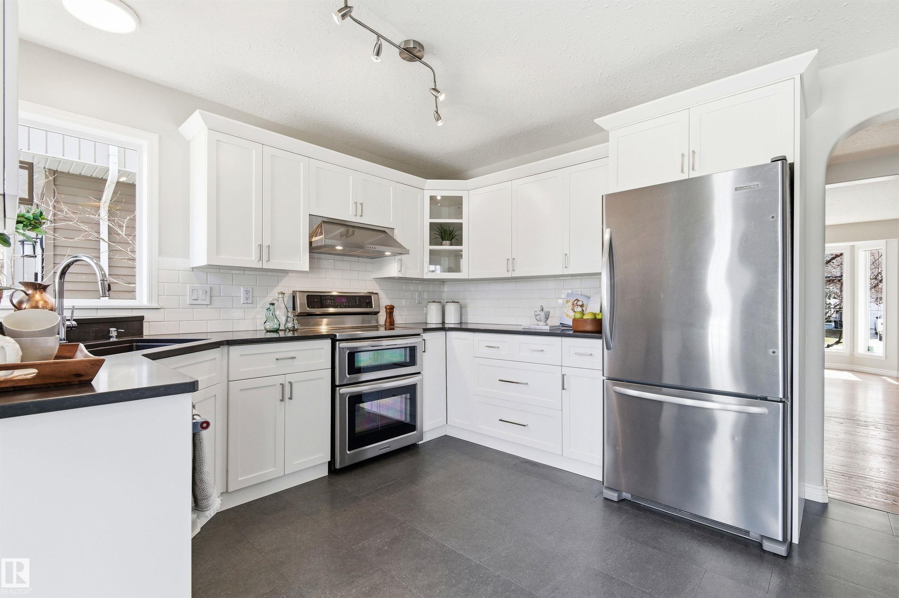 Modern kitchen featuring white cabinetry and dark countertops - 8730 92A Avenue, Edmonton, AB - Indoor Photo Showing Kitchen With Upgraded Kitchen