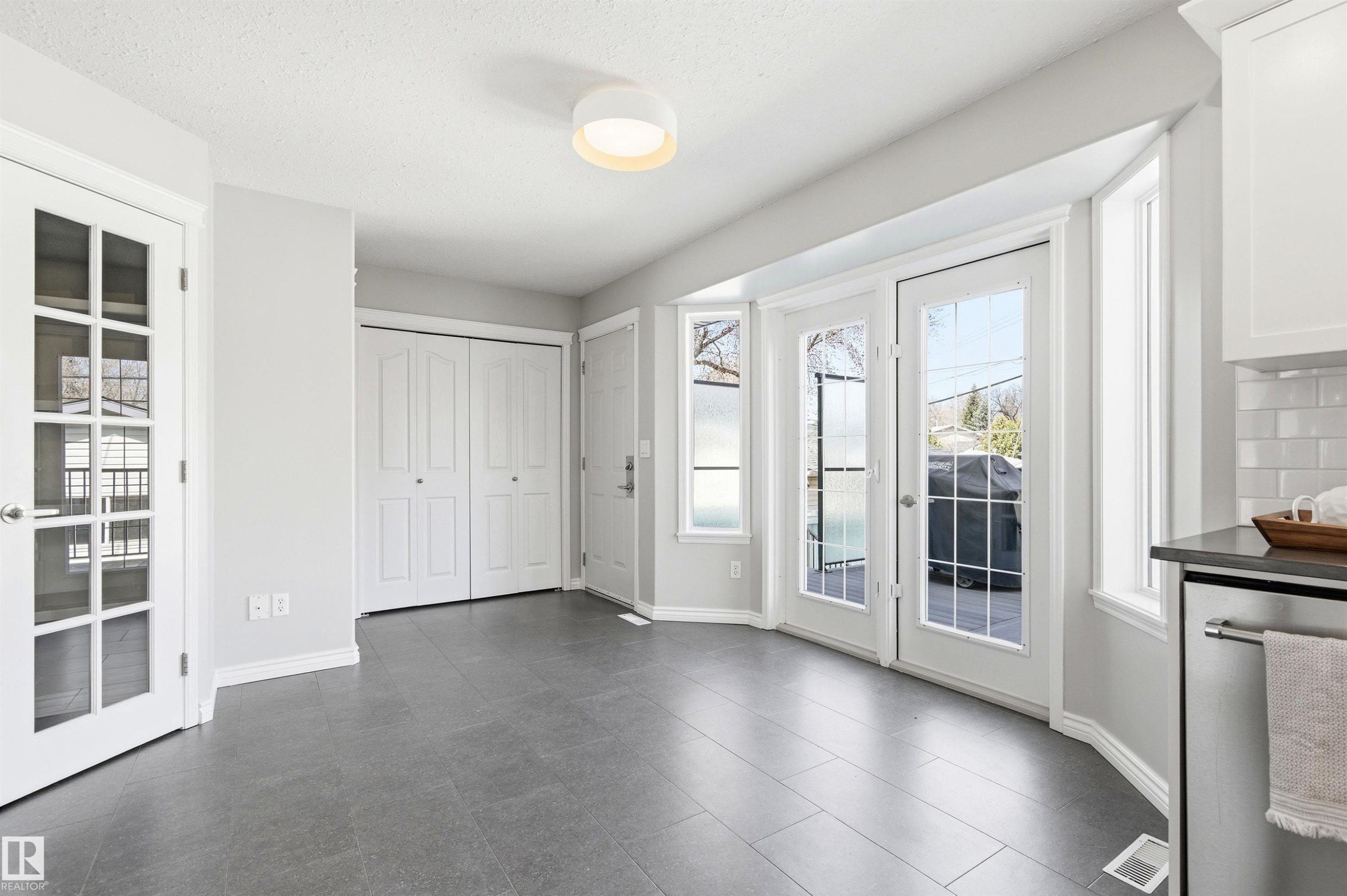 Kitchen area featuring dark tile flooring, white shaker-style cabinetry, and a subway tile backsplash - 8730 92A Avenue, Edmonton, AB - Indoor Photo Showing Other Room