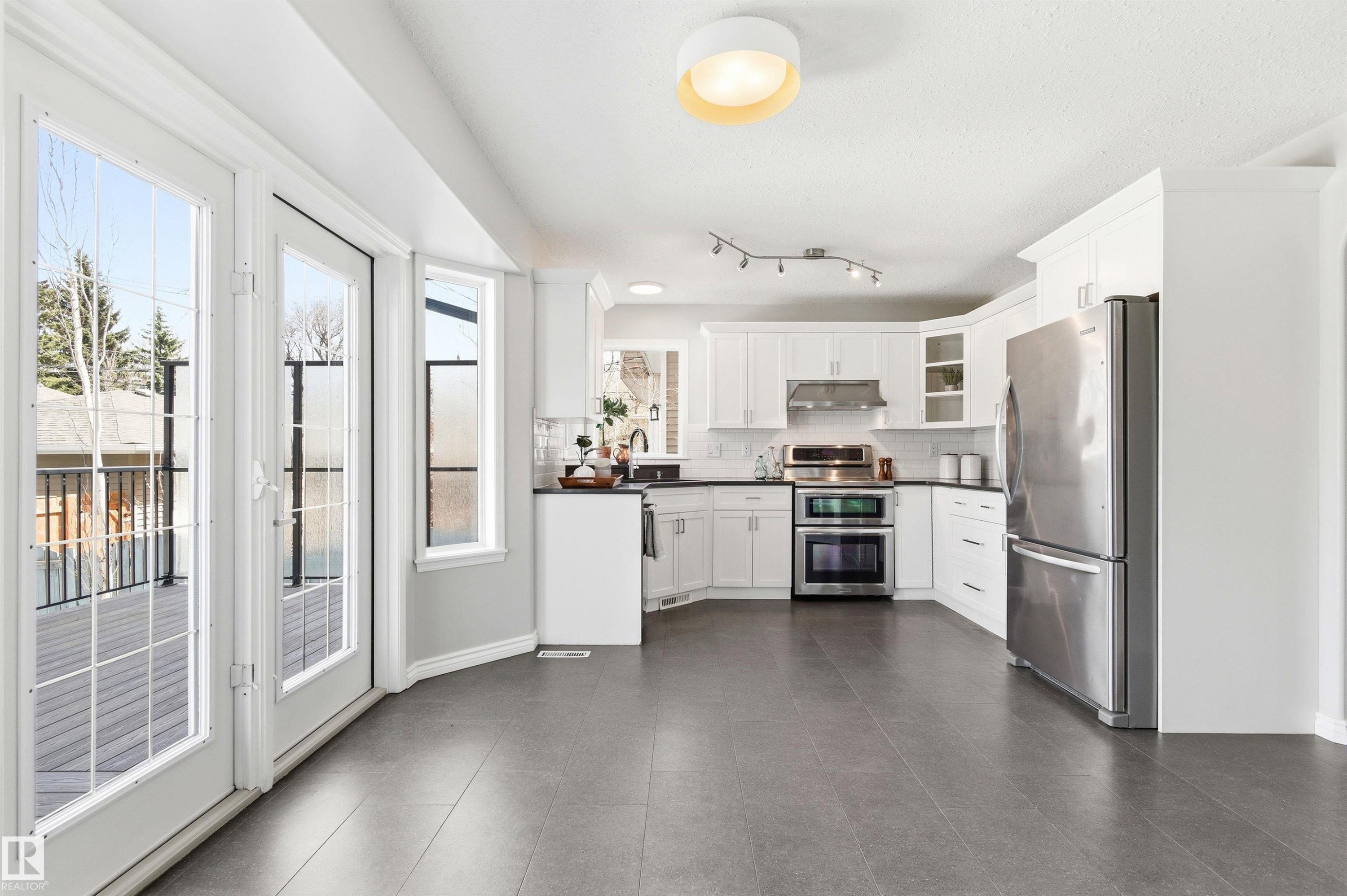Kitchen featuring white cabinetry, dark countertops, stainless steel appliances, and a tile backsplash - 8730 92A Avenue, Edmonton, AB - Indoor Photo Showing Kitchen With Upgraded Kitchen
