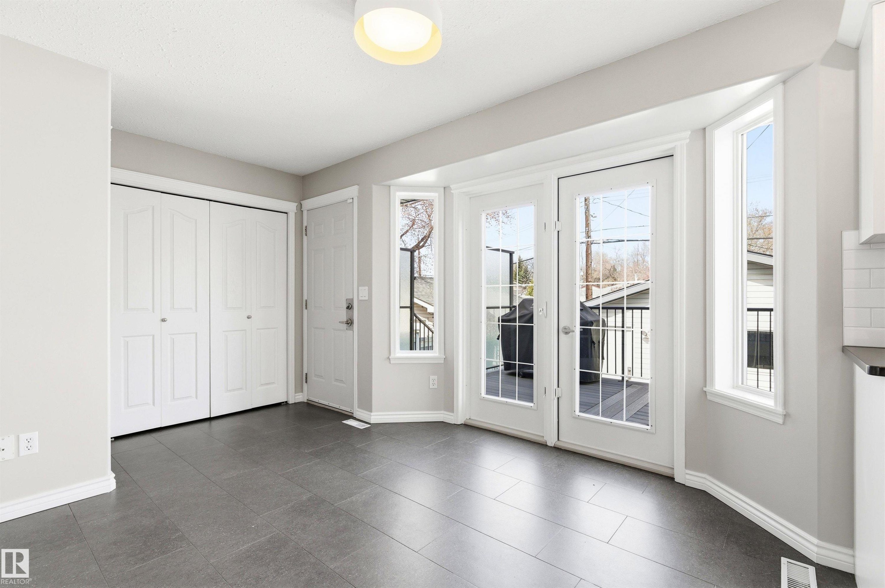 Spacious room featuring gray tile flooring, white baseboards, and a contemporary flush mount ceiling light - 8730 92A Avenue, Edmonton, AB - Indoor Photo Showing Other Room