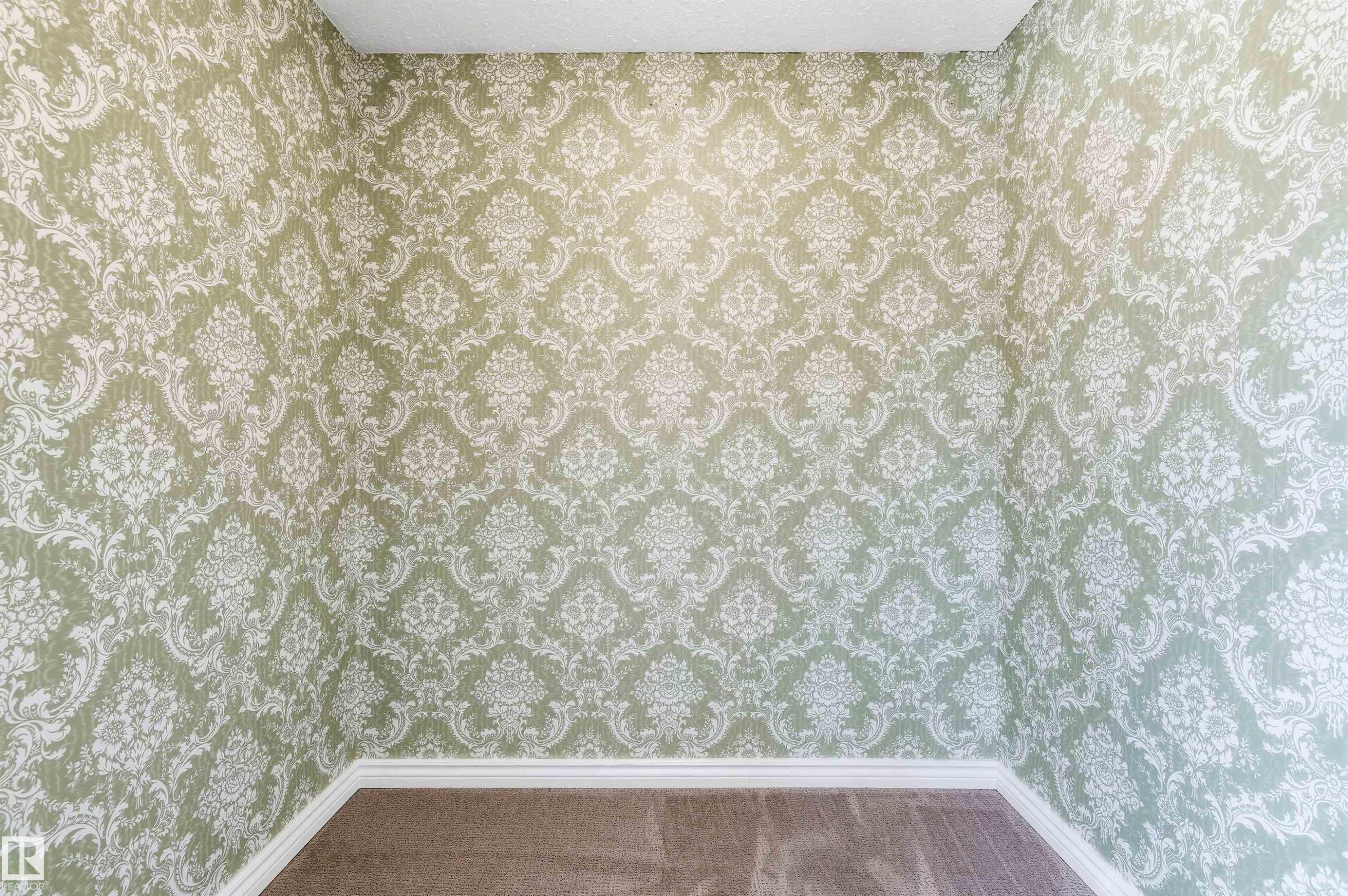 Room featuring light green and white damask-patterned wallpaper, white baseboards, and carpet flooring - 8730 92A Avenue, Edmonton, AB -