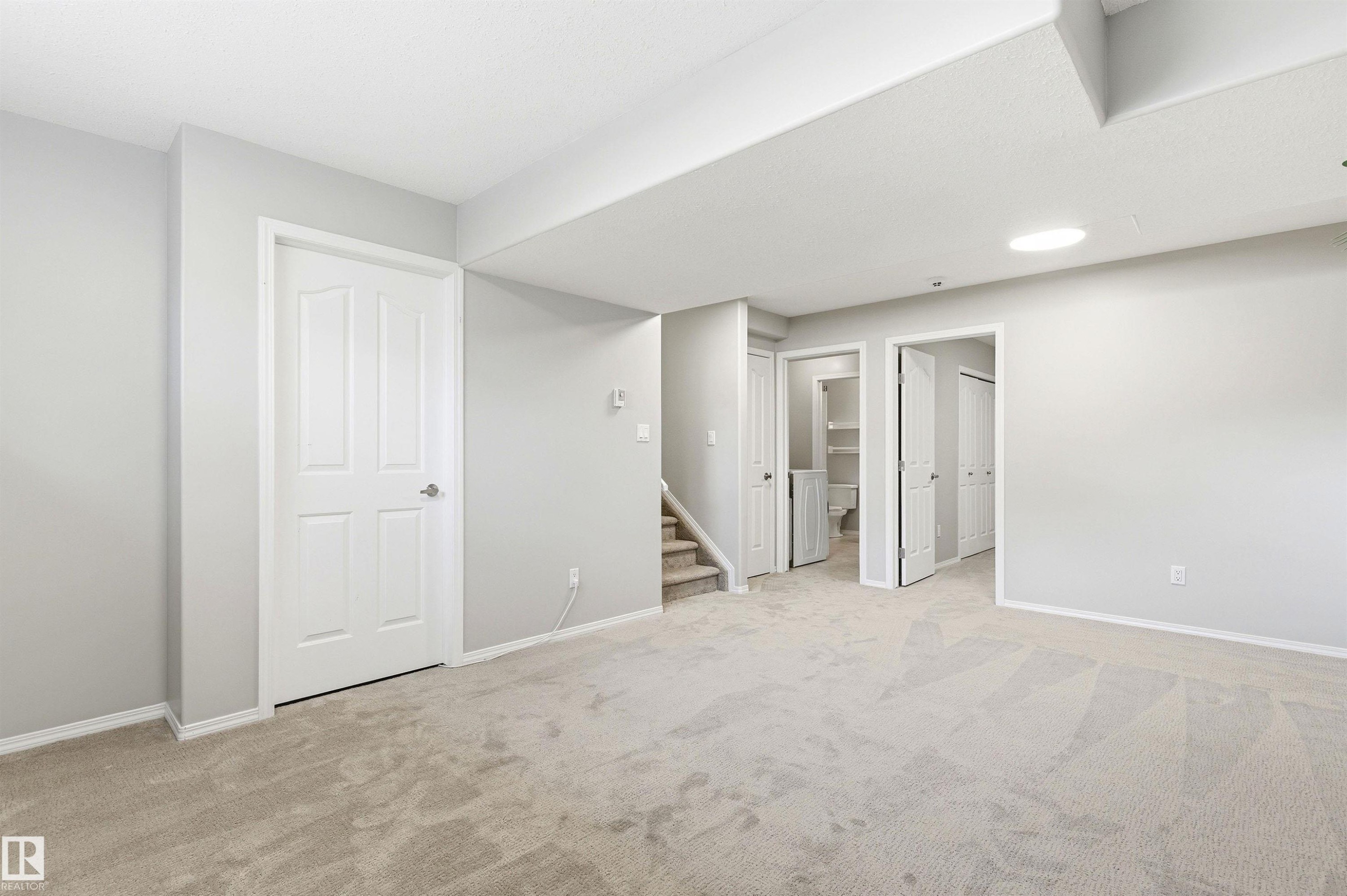 Spacious room featuring light gray walls, plush carpet flooring, white trim, and multiple doorways - 8730 92A Avenue, Edmonton, AB - Indoor Photo Showing Other Room