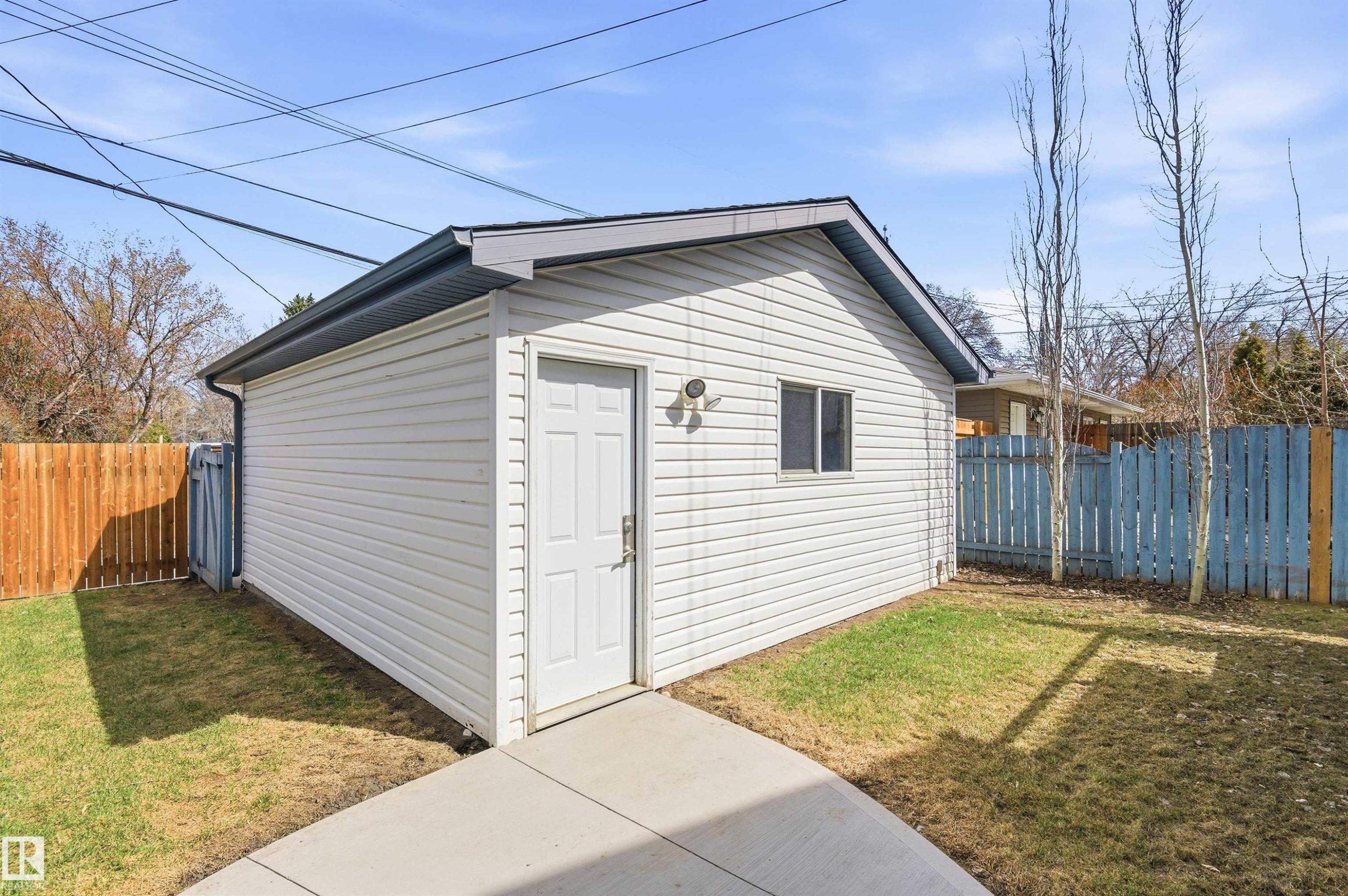 Detached white vinyl-sided structure featuring a single-panel door, small window, and dark gray shingle roof - 8730 92A Avenue, Edmonton, AB - Outdoor With Exterior