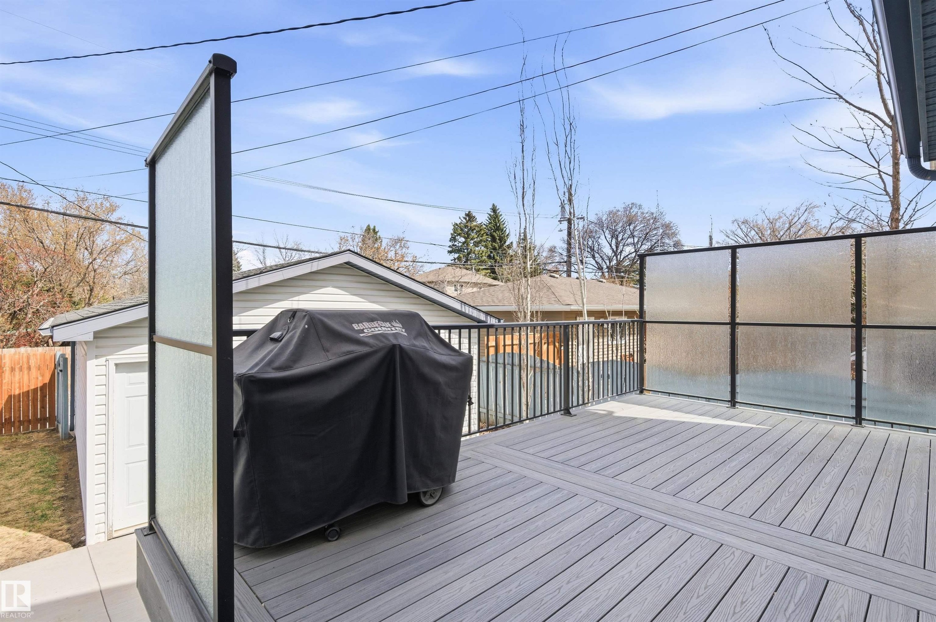 Spacious exterior deck featuring composite decking, black metal railings, and frosted privacy screens - 8730 92A Avenue, Edmonton, AB - Outdoor With Deck Patio Veranda With Exterior