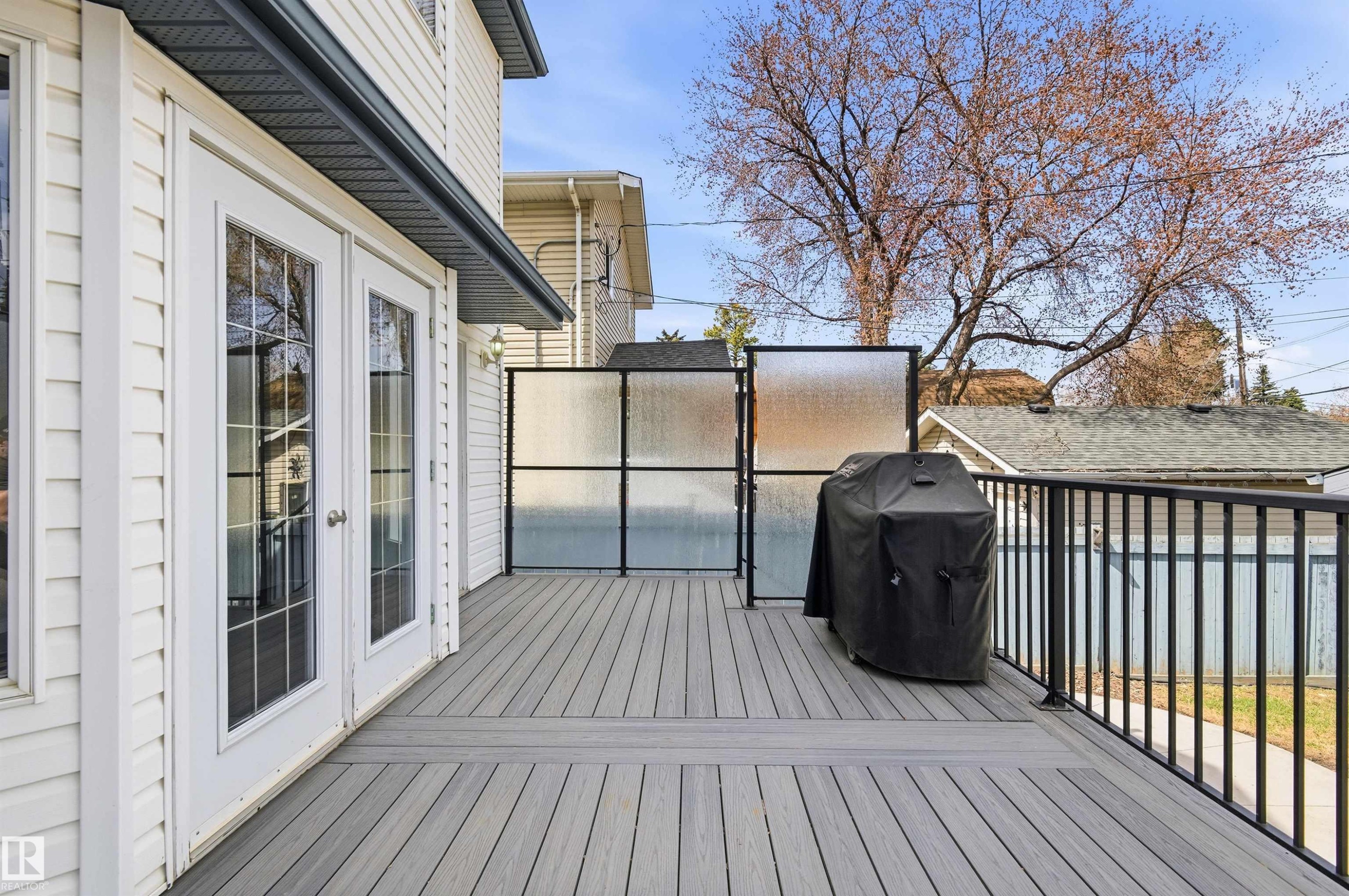 Spacious outdoor deck featuring composite decking, black metal railings, and frosted privacy screens - 8730 92A Avenue, Edmonton, AB - Outdoor With Deck Patio Veranda With Exterior