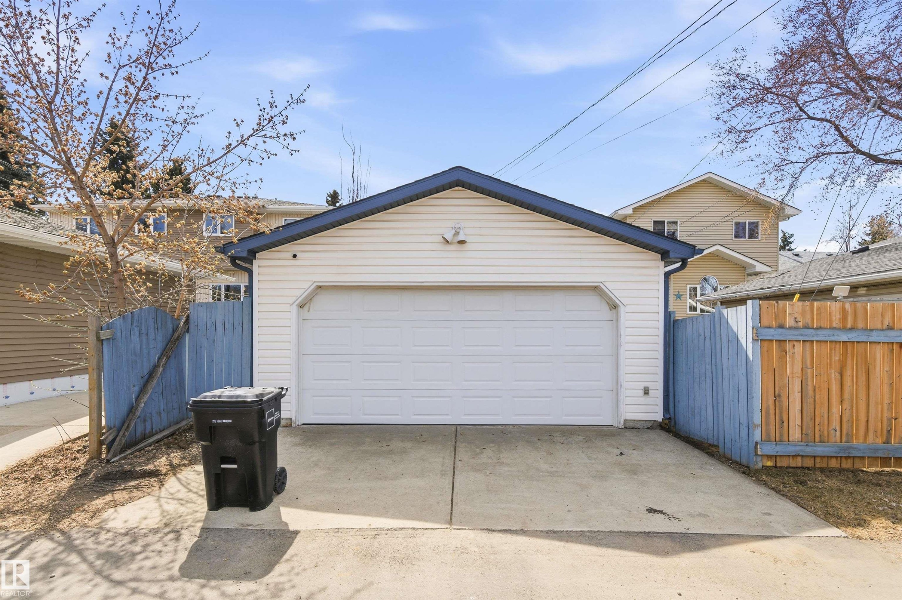 Detached garage with white vinyl siding, a dark blue shingle roof, and a white panel garage door - 8730 92A Avenue, Edmonton, AB - Outdoor With Exterior
