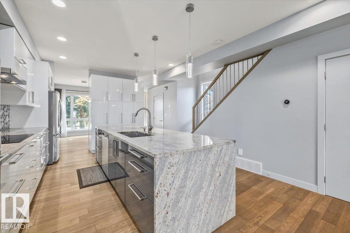Modern kitchen featuring a waterfall island with an undermount sink and gooseneck faucet - 8706 88 Avenue, Edmonton, AB - Indoor Photo Showing Kitchen With Upgraded Kitchen