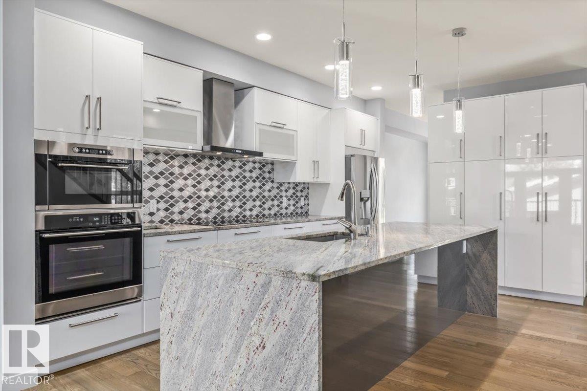 Gourmet kitchen featuring a large waterfall island with stone countertop, integrated sink, and pull-down faucet - 8706 88 Avenue, Edmonton, AB - Indoor Photo Showing Kitchen With Stainless Steel Kitchen With Upgraded Kitchen