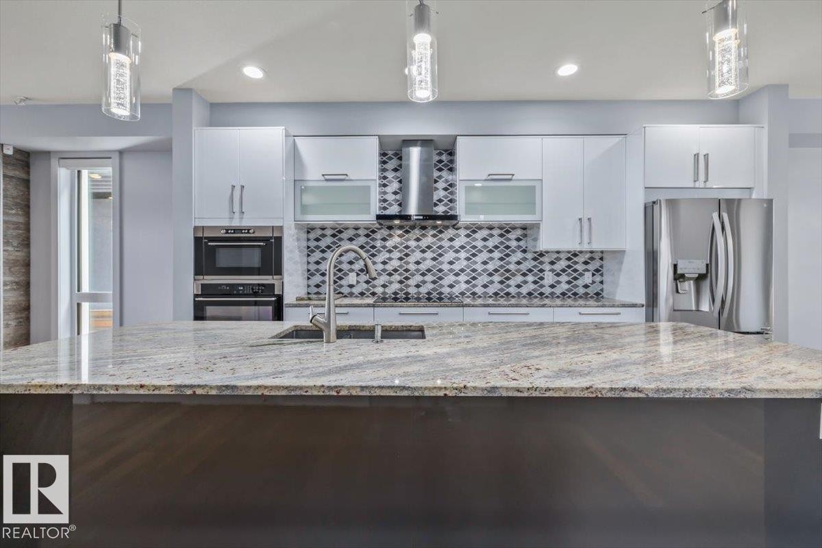 Kitchen featuring a large island with a stone countertop, an undermount sink, and a gooseneck faucet - 8706 88 Avenue, Edmonton, AB - Indoor Photo Showing Kitchen With Upgraded Kitchen