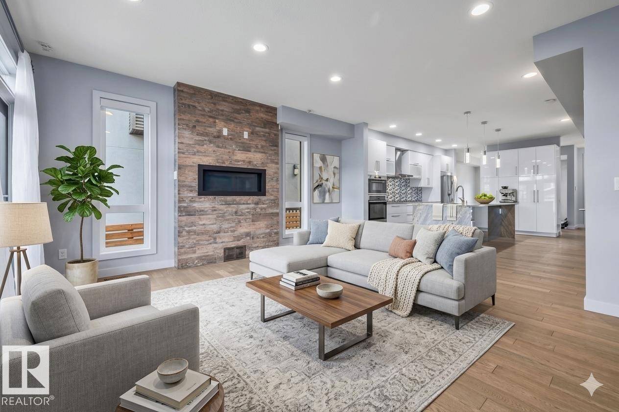 Open-concept living space featuring wood-finish flooring, recessed lighting, and a stone-clad fireplace with an integrated modern firebox - 8706 88 Avenue, Edmonton, AB - Indoor Photo Showing Living Room With Fireplace