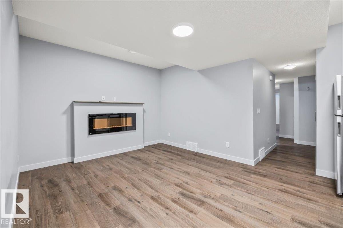 Living area featuring a sleek, wall-mounted electric fireplace with a floating mantel - 8706 88 Avenue, Edmonton, AB - Indoor Photo Showing Living Room With Fireplace