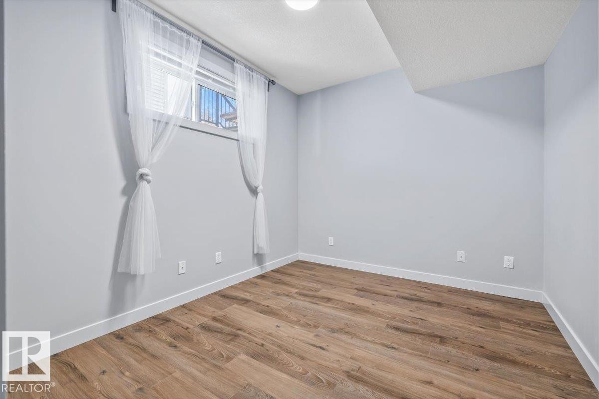 Room with wood-finish flooring, light grey painted walls, and white baseboards - 8706 88 Avenue, Edmonton, AB - Indoor Photo Showing Other Room