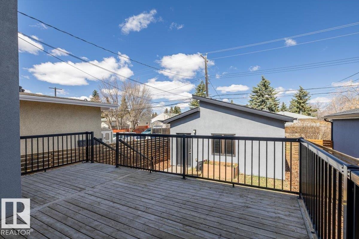 Spacious outdoor deck featuring wood-finish flooring and black metal railings - 8706 88 Avenue, Edmonton, AB - Outdoor With Deck Patio Veranda With Exterior