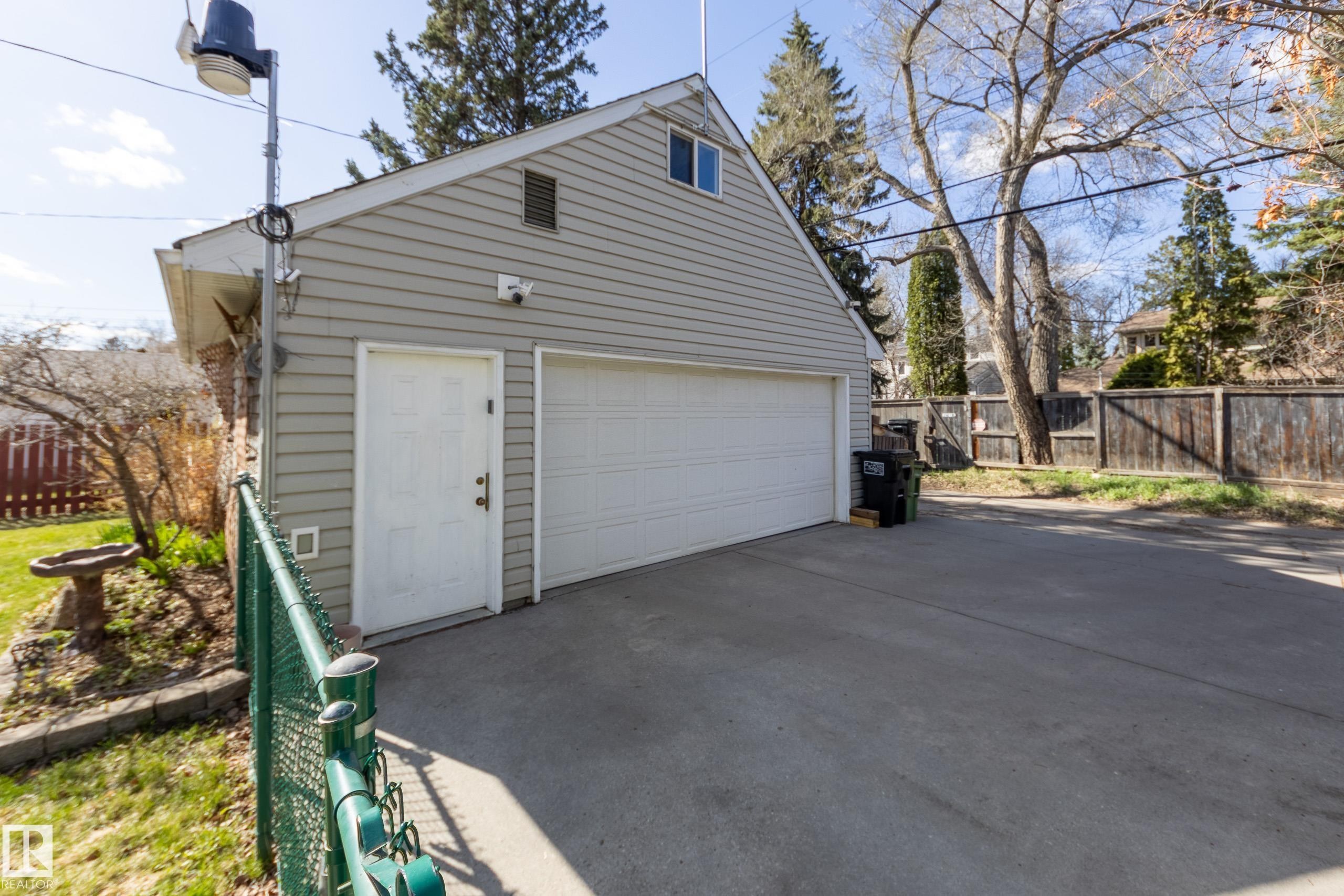 Detached two-car garage with light gray siding and a white paneled door - 11516 72 Avenue, Edmonton, AB - Outdoor