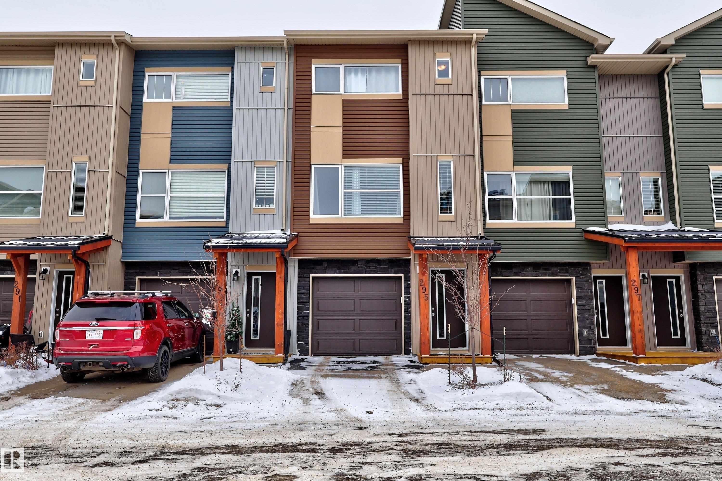 Contemporary townhome featuring a multi-tone facade with horizontal and vertical siding, a private garage, and a covered entry porch with wood accents - 295 401 Southfork, Leduc, AB - Outdoor With Facade