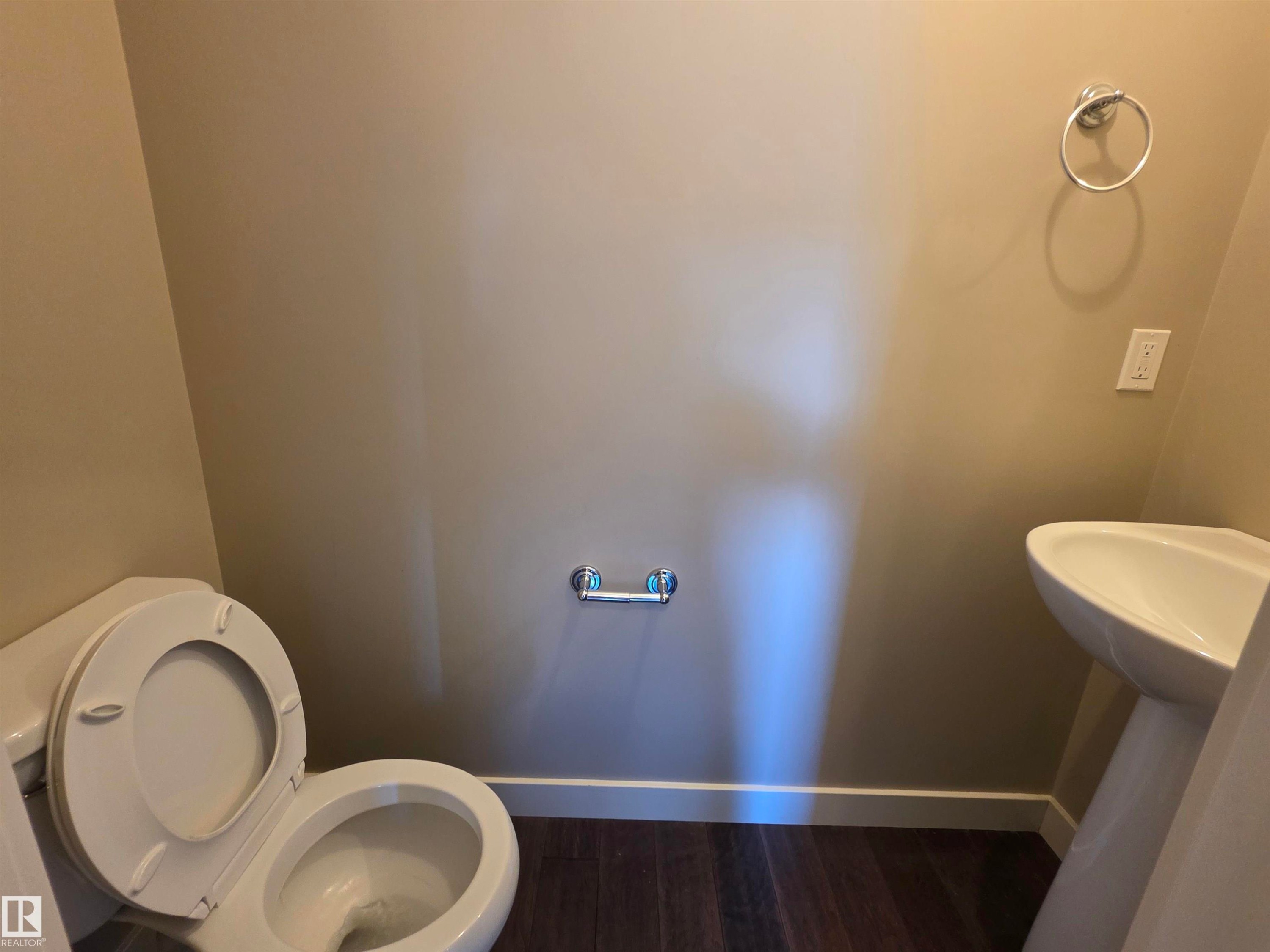 Pedestal sink with white toilet and wood-finish flooring - 295 401 Southfork, Leduc, AB - Indoor Photo Showing Bathroom