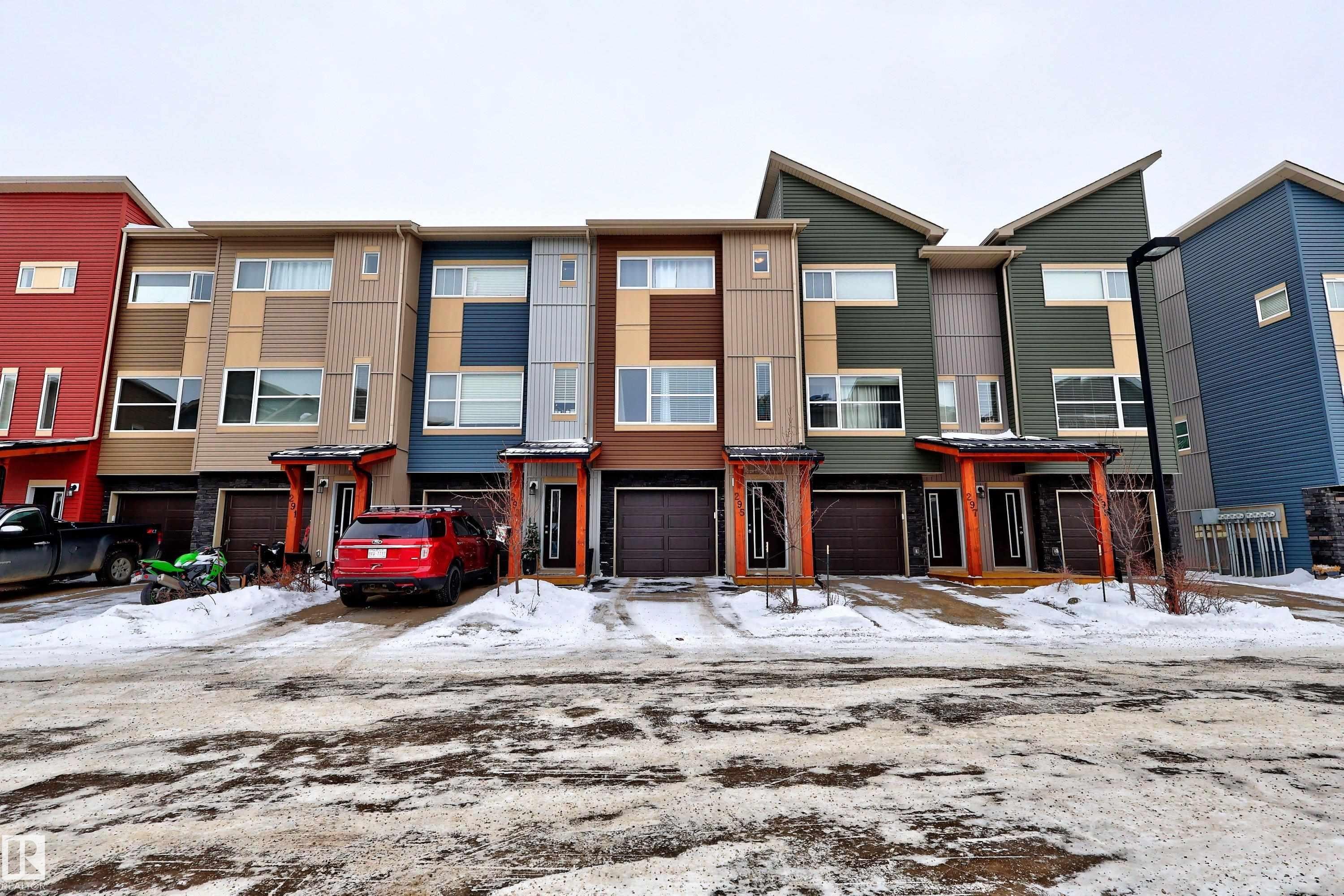 Modern townhome exteriors featuring varied siding materials, attached garages, and covered entryways - 295 401 Southfork, Leduc, AB - Outdoor With Facade
