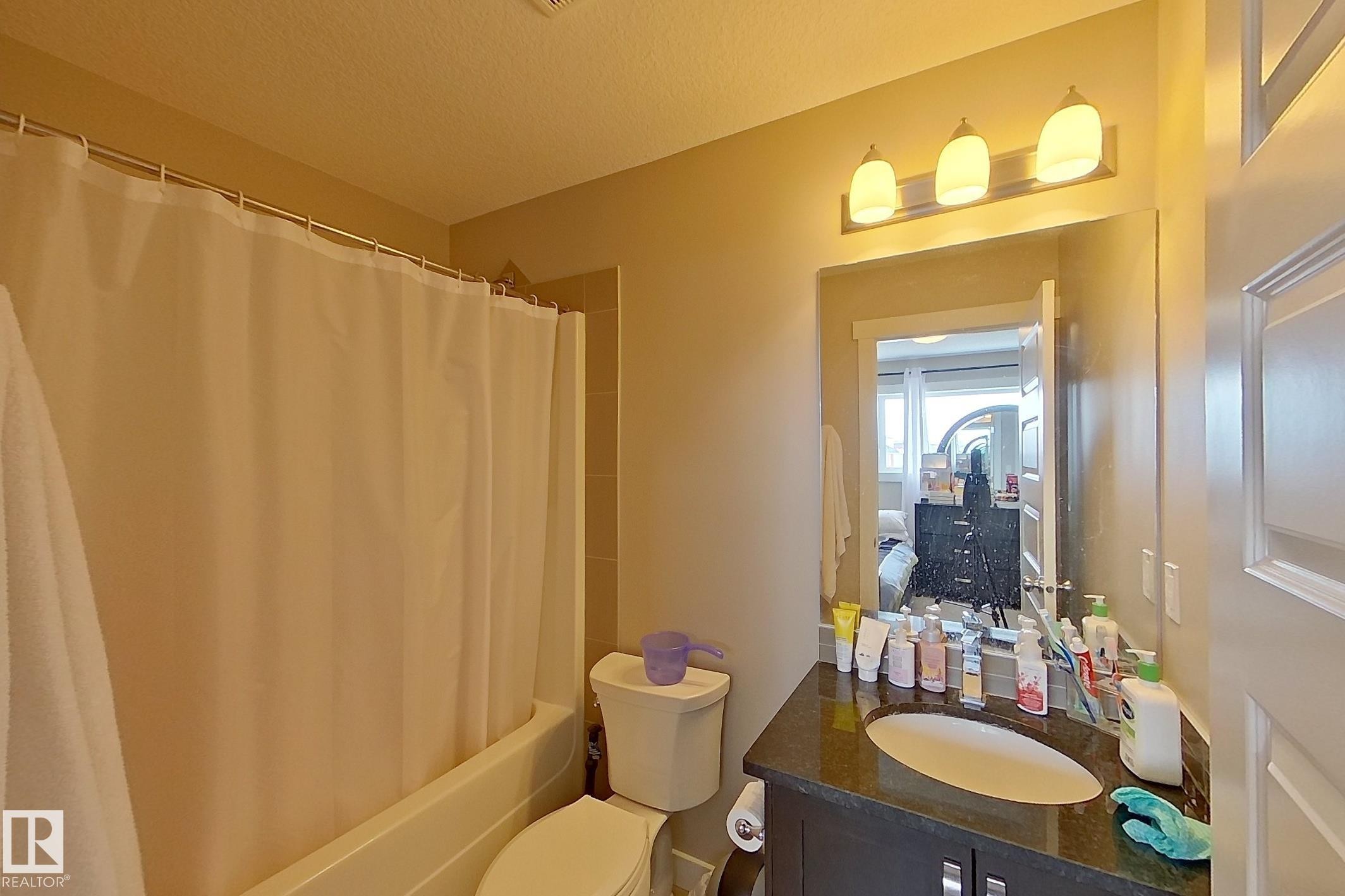 Bathroom featuring a dark wood-finish vanity with an undermount sink, a dark countertop, and a three-bulb vanity light fixture - 295 401 Southfork, Leduc, AB - Indoor Photo Showing Bathroom