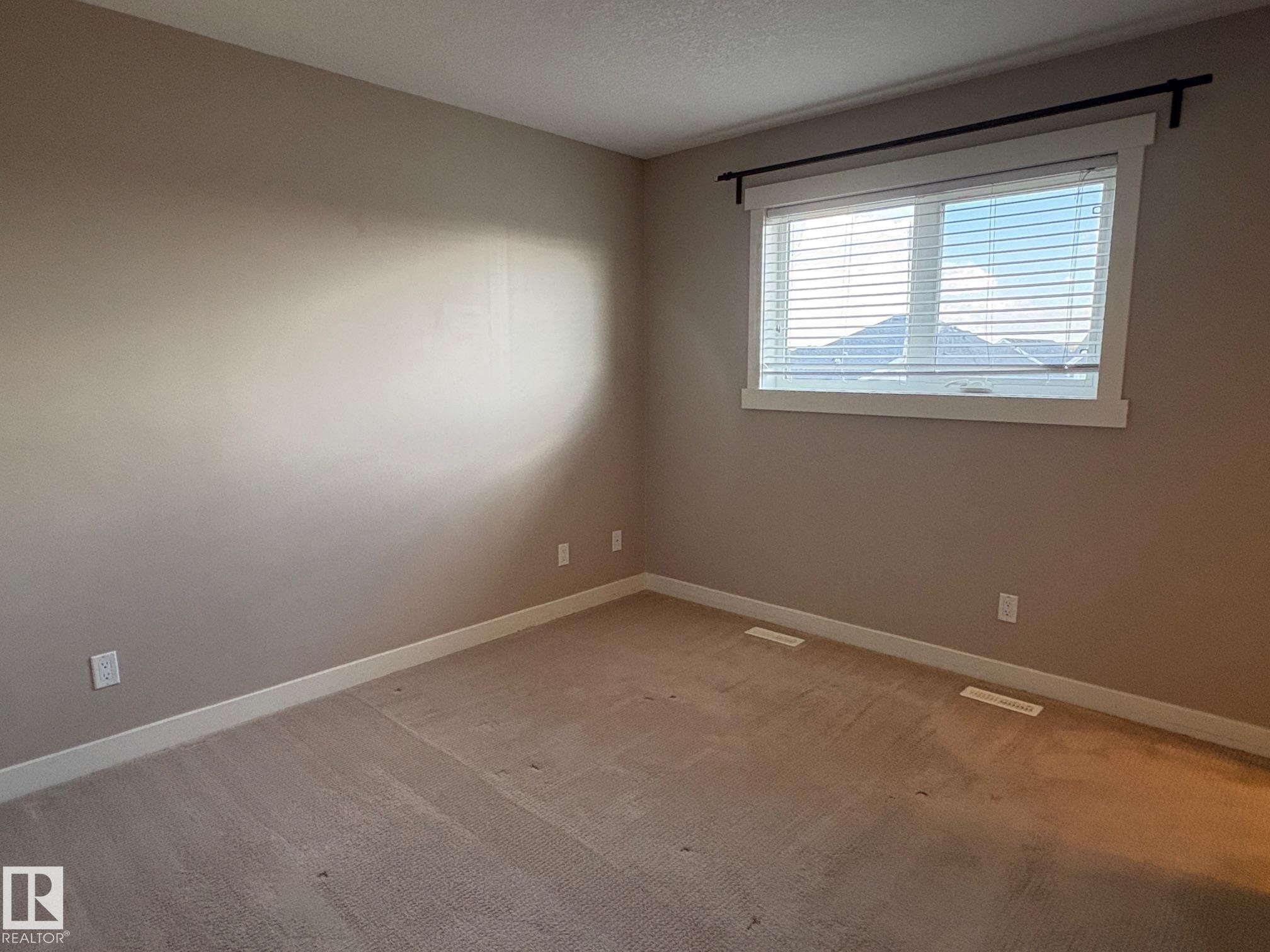 Neutral-toned carpeting and walls complement the white trim and window blinds - 295 401 Southfork, Leduc, AB - Indoor Photo Showing Other Room
