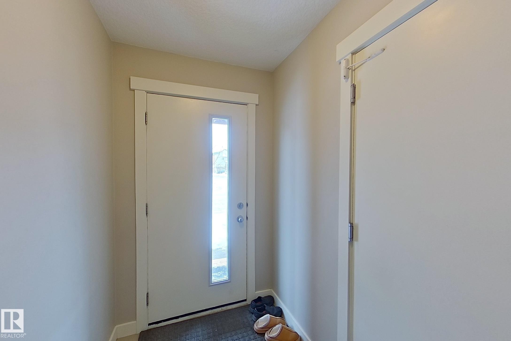 Entryway featuring a white door with vertical glass paneling, neutral wall tones, and a dark floor mat - 295 401 Southfork, Leduc, AB - Indoor Photo Showing Other Room