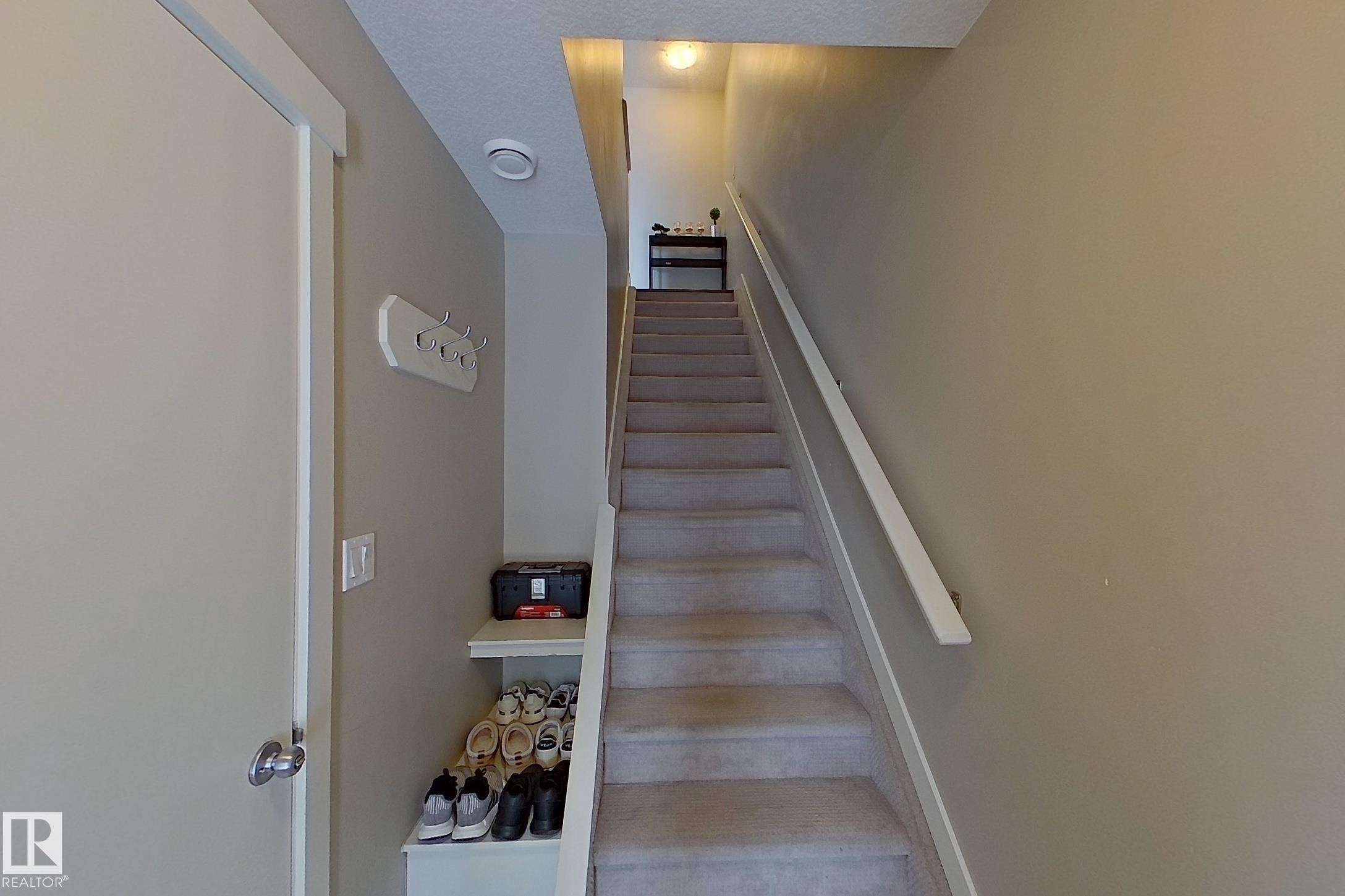 Carpeted staircase featuring a light-colored handrail, recessed lighting, and a built-in storage niche - 295 401 Southfork, Leduc, AB - Indoor Photo Showing Other Room