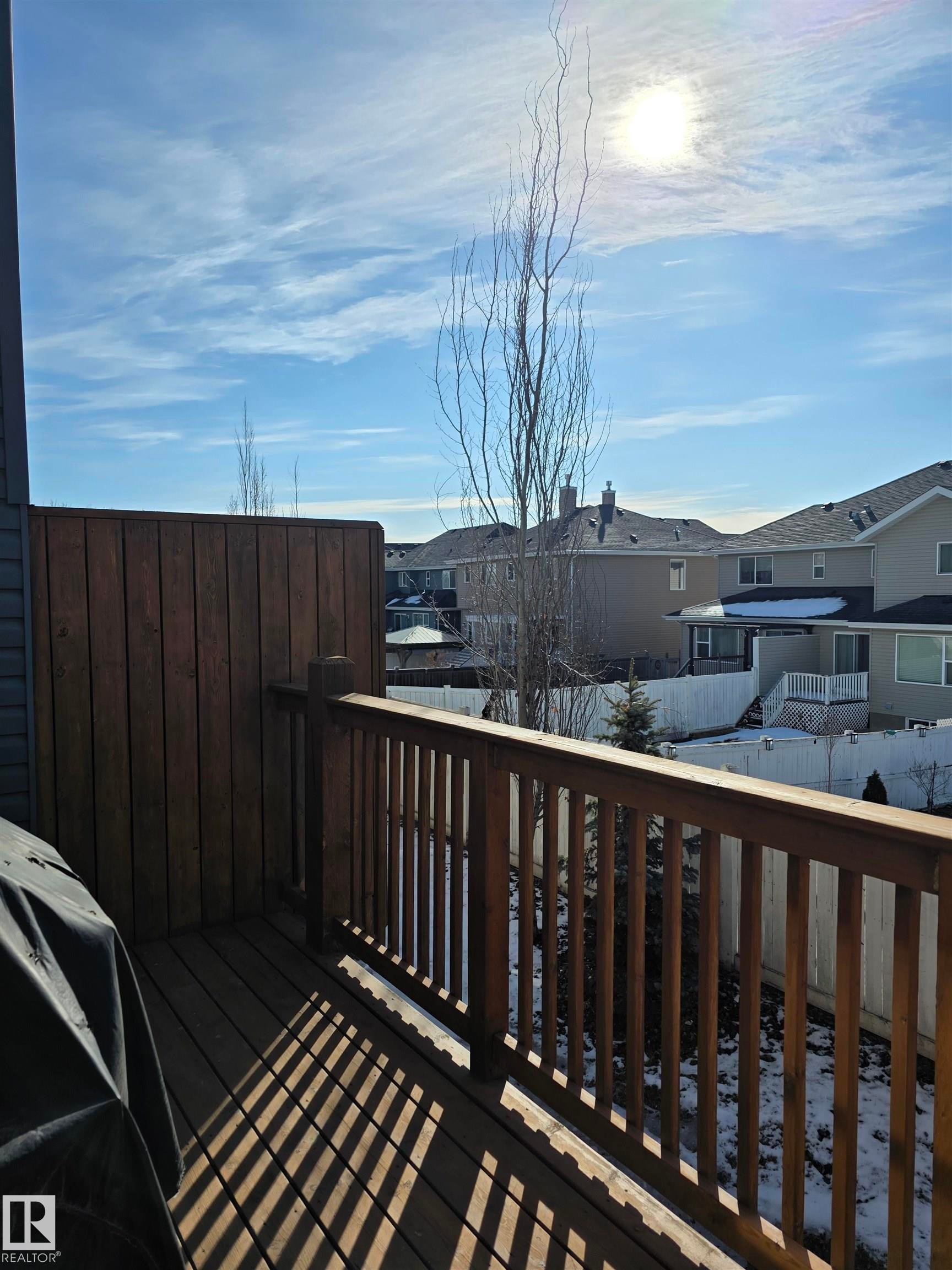 Private wood deck featuring a slatted privacy wall and wood baluster railing - 295 401 Southfork, Leduc, AB - Outdoor With Balcony