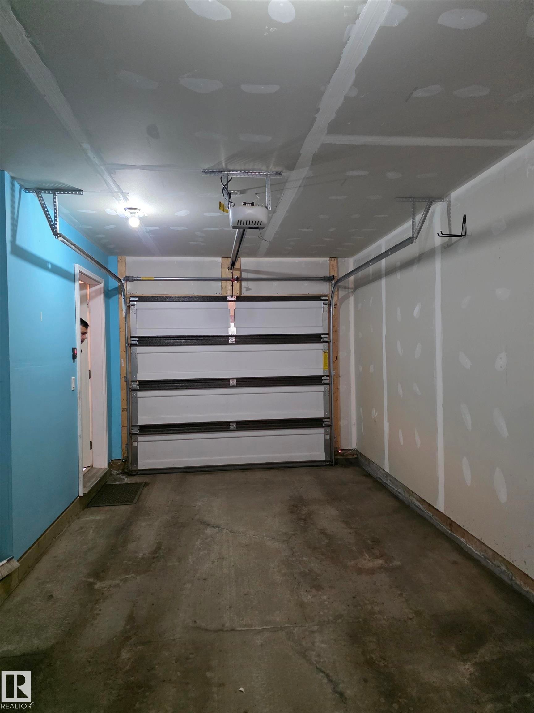 Spacious garage featuring a concrete floor, an automatic garage door opener, and interior wall access - 295 401 Southfork, Leduc, AB - Indoor Photo Showing Garage