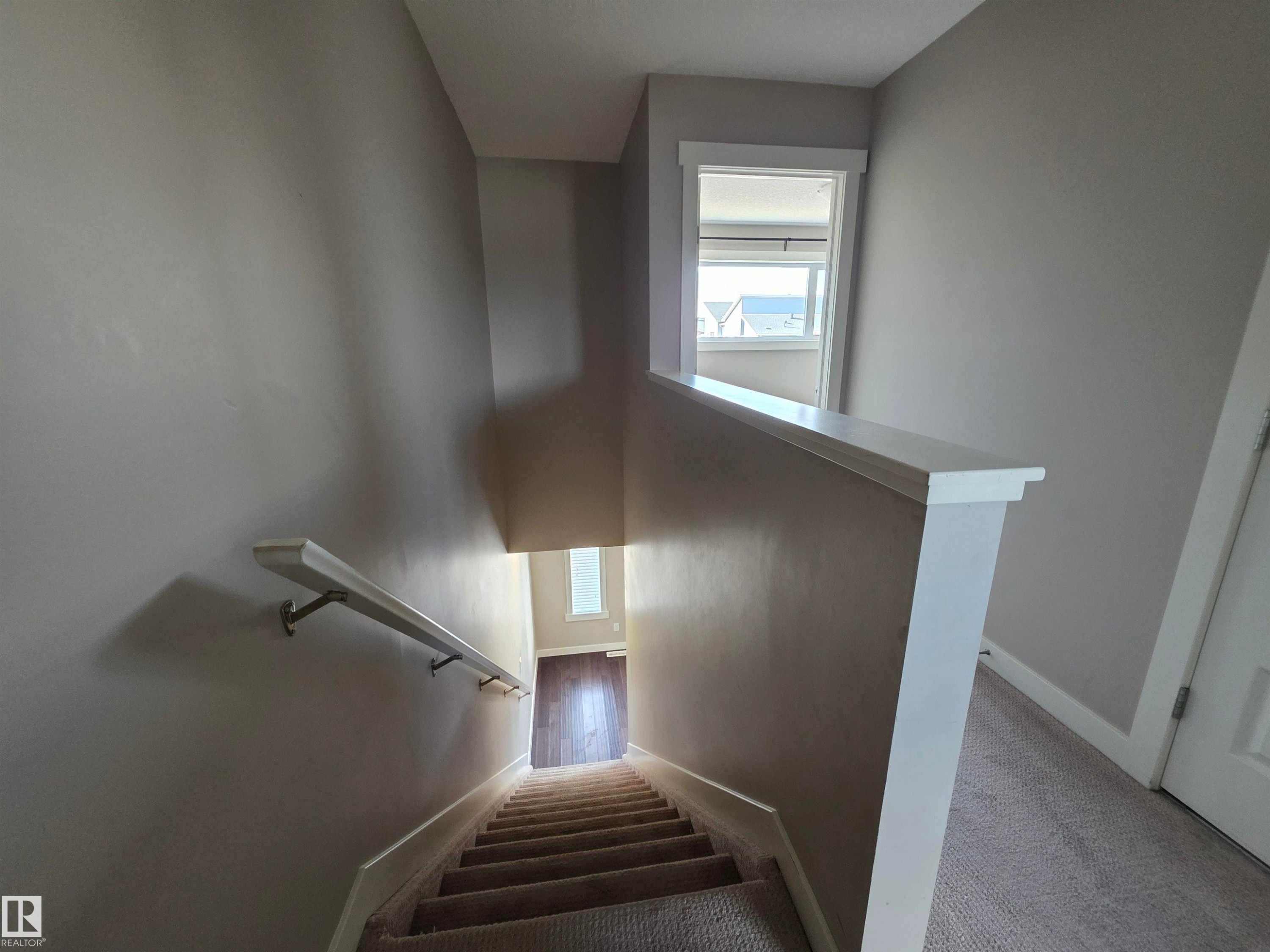 Carpeted staircase with light gray wall paint and white baseboards - 295 401 Southfork, Leduc, AB - Indoor Photo Showing Other Room
