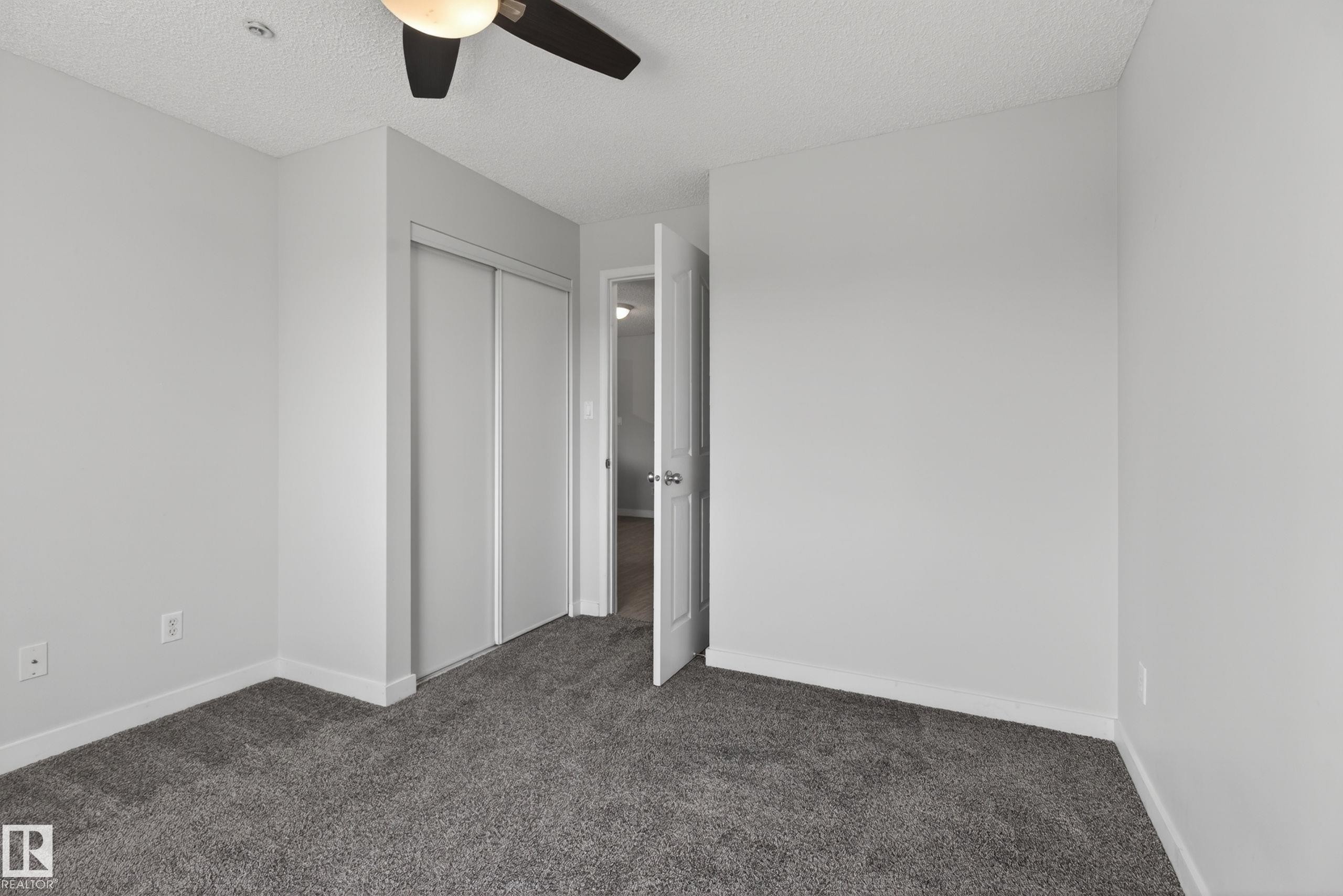 Neutral paint finishes on walls and trim, plush grey carpeting, and a ceiling fan with integrated lighting - #319 16303 95 St Nw, Edmonton, AB - Indoor Photo Showing Other Room