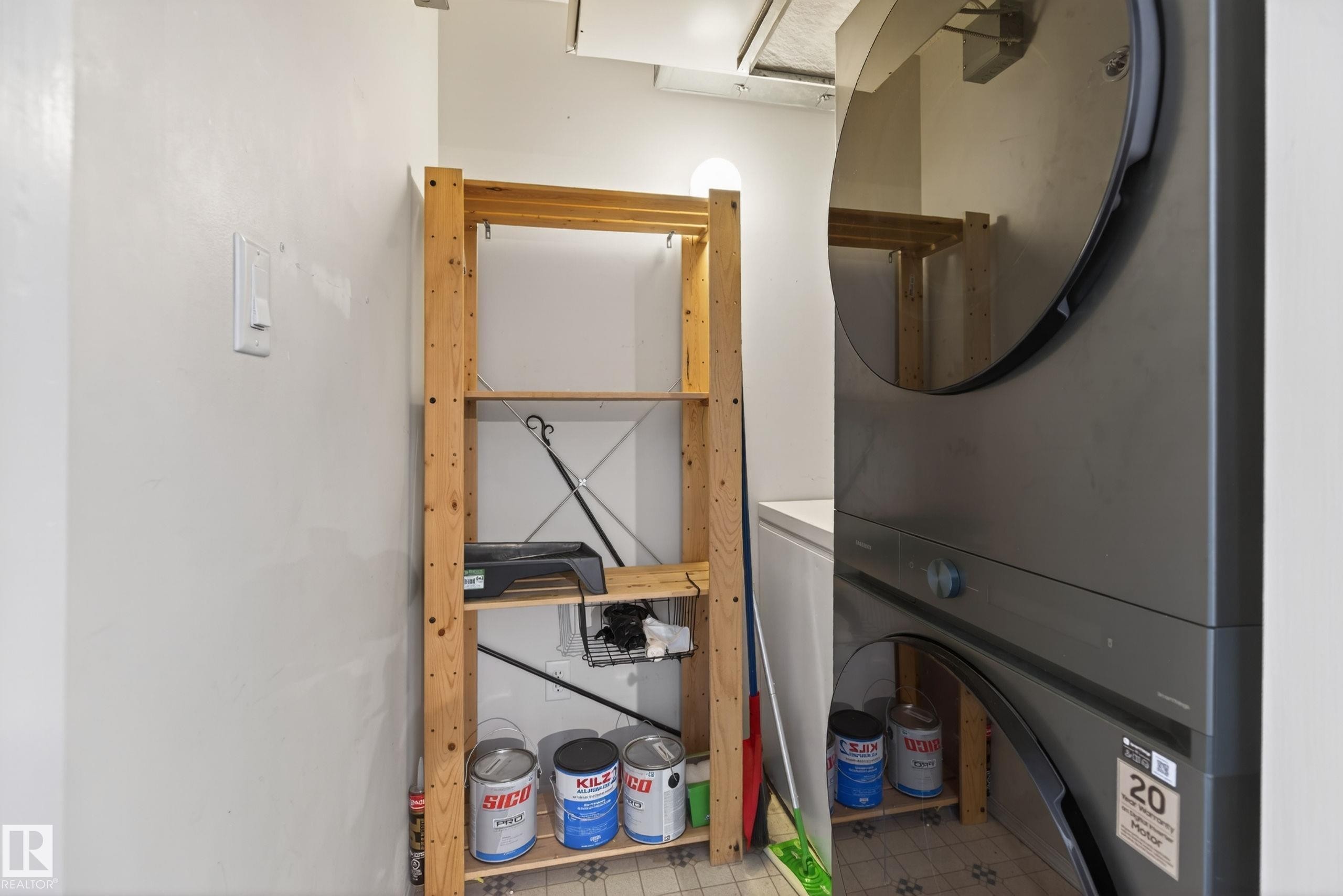 Laundry closet with stacked appliances and adjacent wood shelving unit - #319 16303 95 St Nw, Edmonton, AB - Indoor