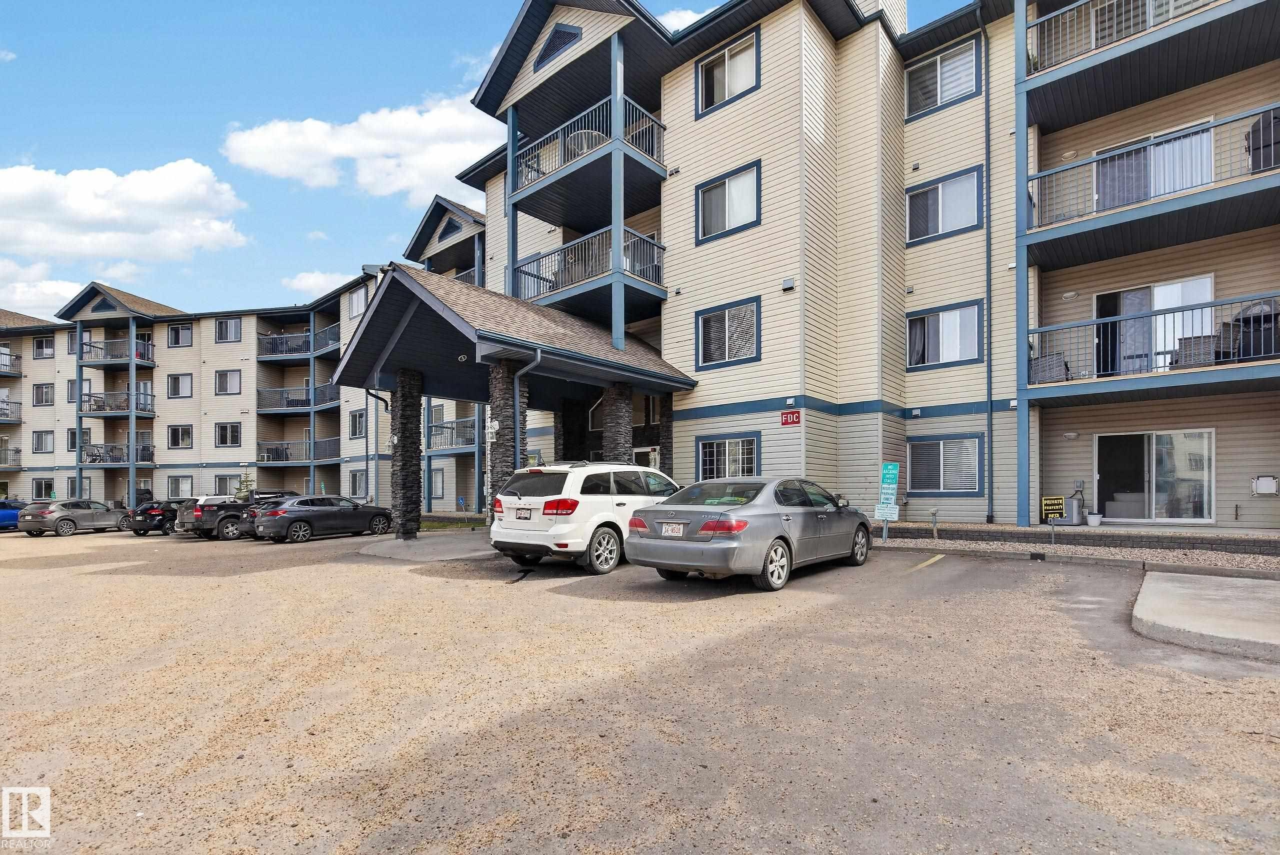 Multi-story residential building featuring light-toned siding and blue trim accents - #319 16303 95 St Nw, Edmonton, AB - Outdoor With Facade