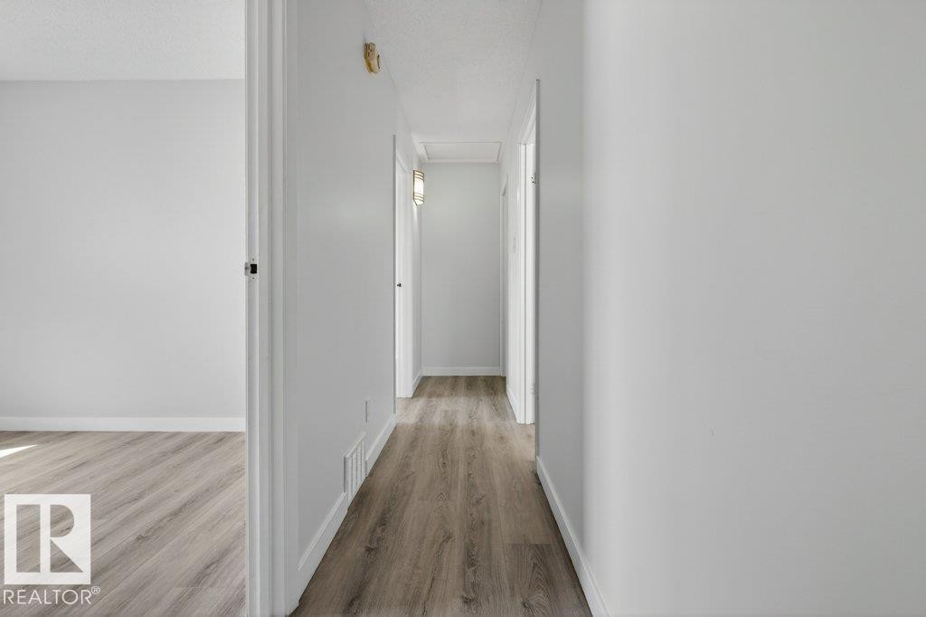 Hallway featuring wood-finish flooring, white baseboards, and light neutral wall paint - 3E Twin Terrace, Edmonton, AB - Indoor Photo Showing Other Room